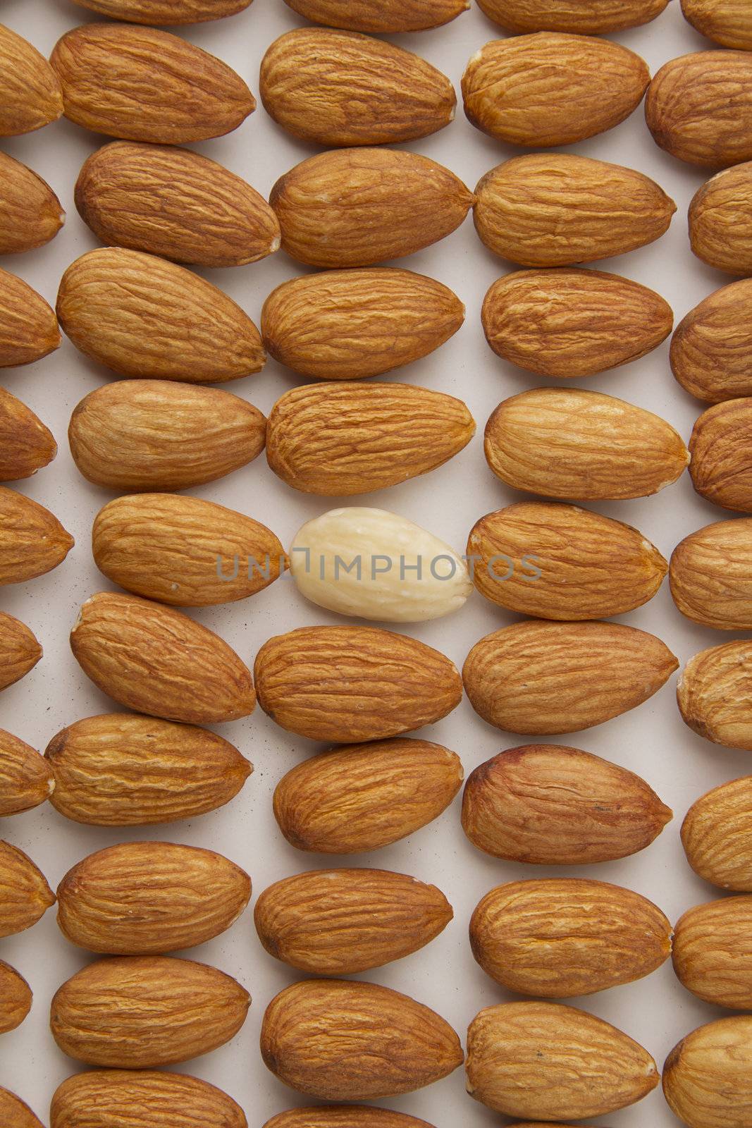 almond put in a row with one peeled almond in the middle