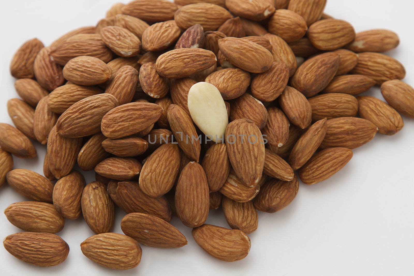 one peeled almond sitting on top of a pile of plain almond