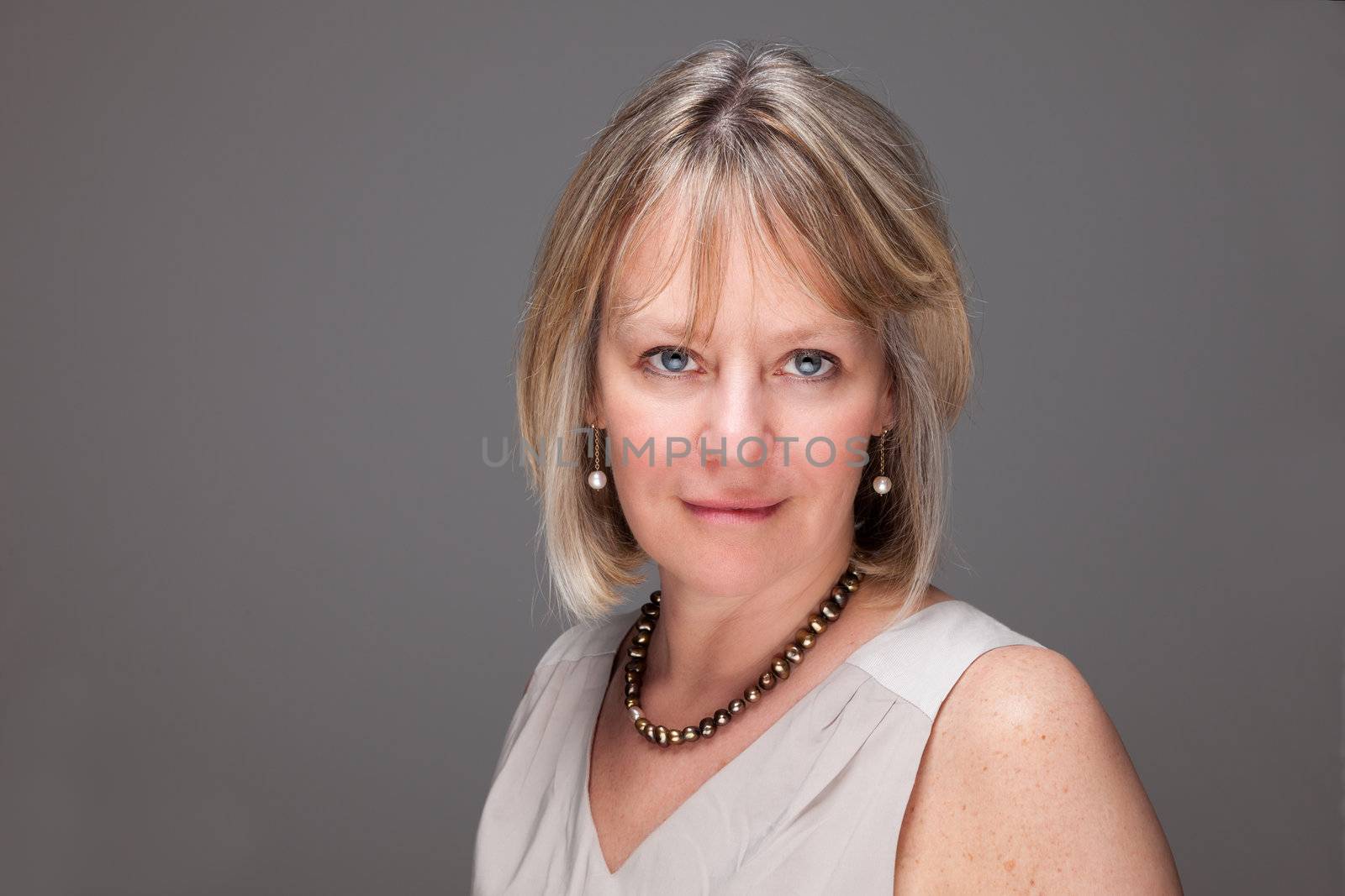 Head Shot Portrait of Attractive Mature Woman with Intense Look on Grey Backround