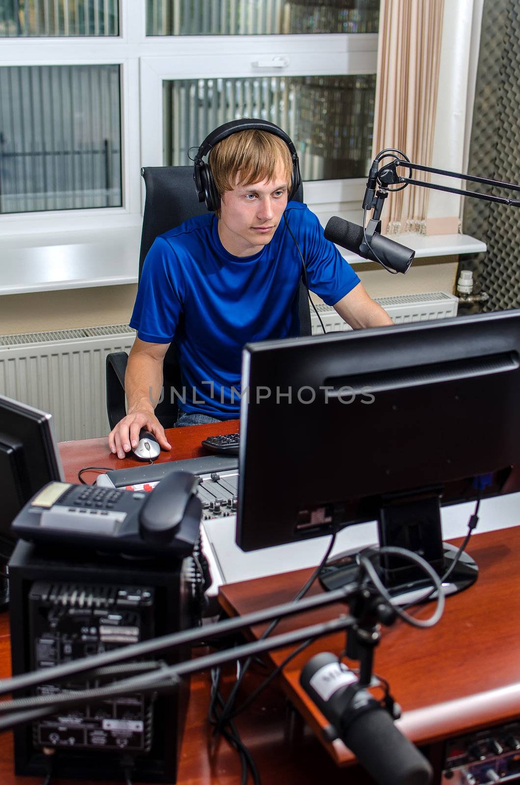 Anchorman sitting in front of a microphone on the radio