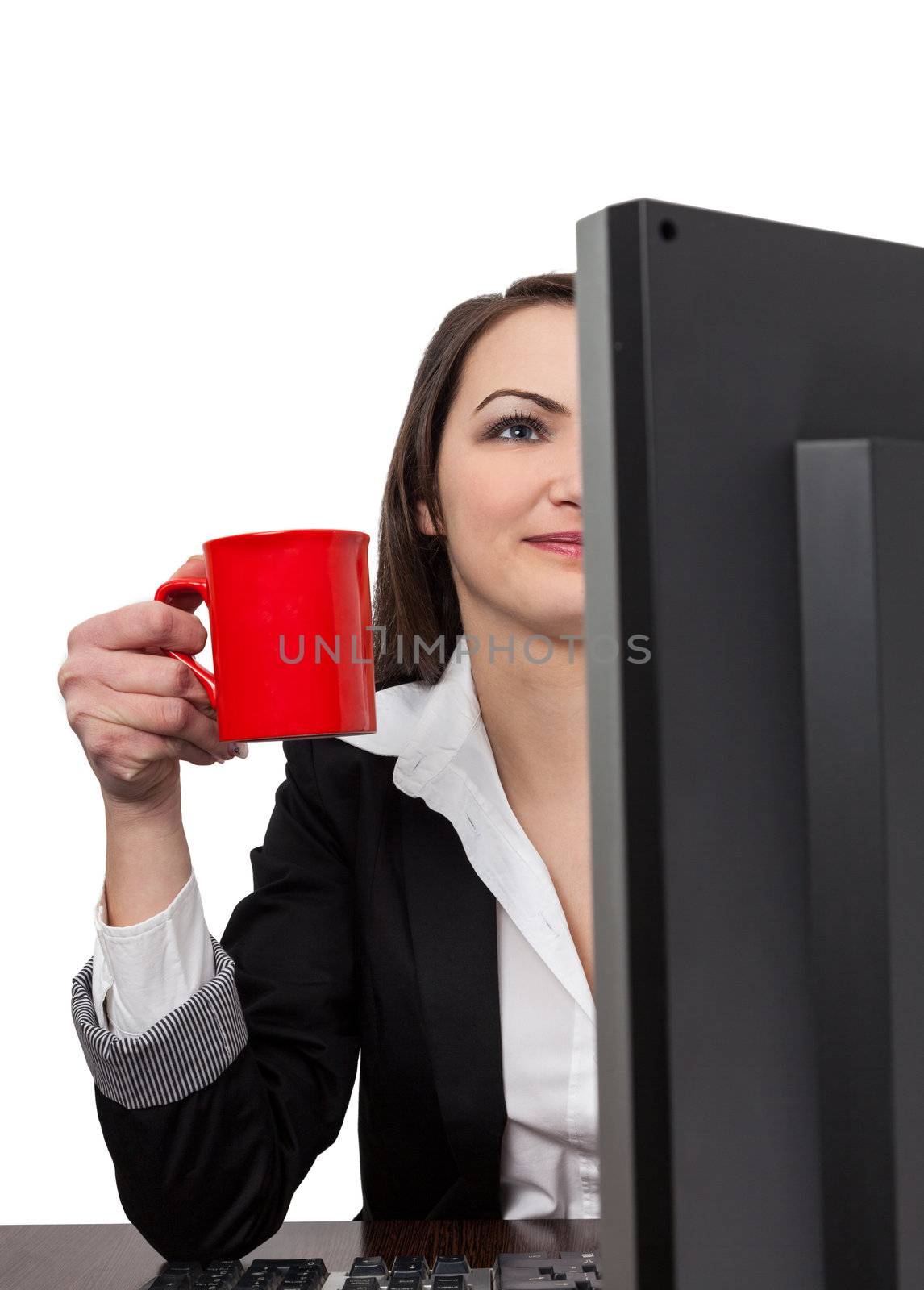 Image of a young businesswoman with a big red cup of coffee in front of her computer at the workplace in the office, isolated against a white background.