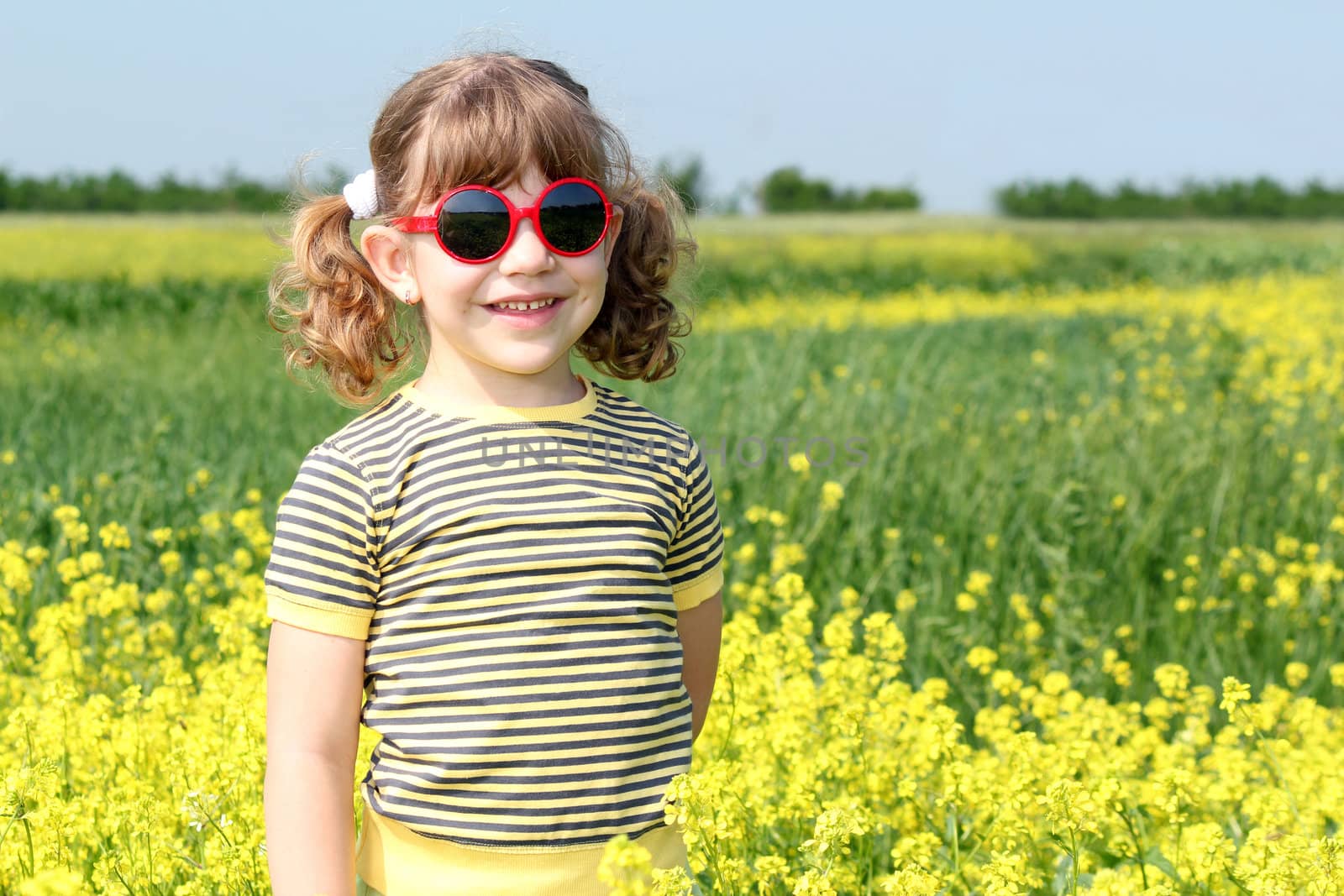 little girl posing in yellow flowers field