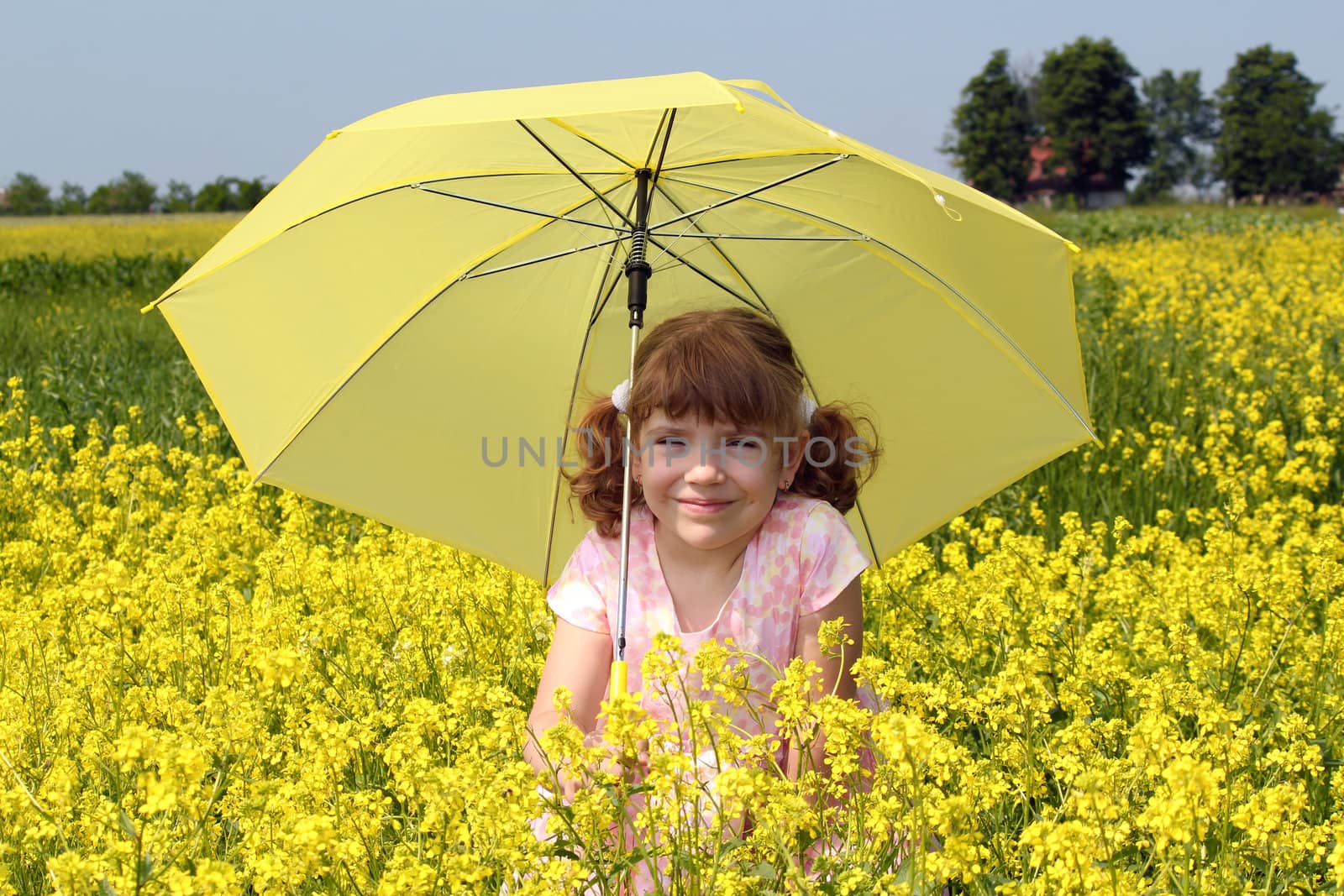 beautiful little girl with umbrella standing in yellow flowers field