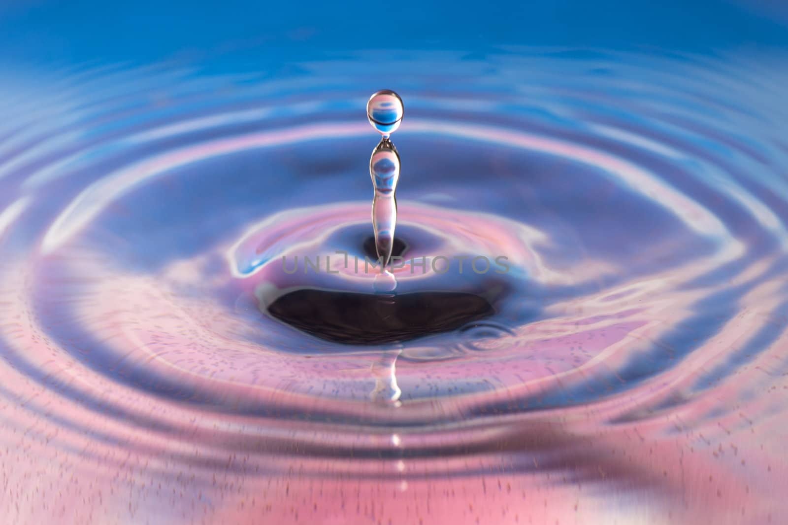 A high speed shot of a drop of water hitting a standing water surface to form a crown effect.