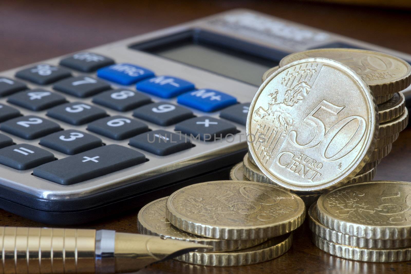 A stack of 50 cents euro coins, pen and a calculator. Focus on currencies.