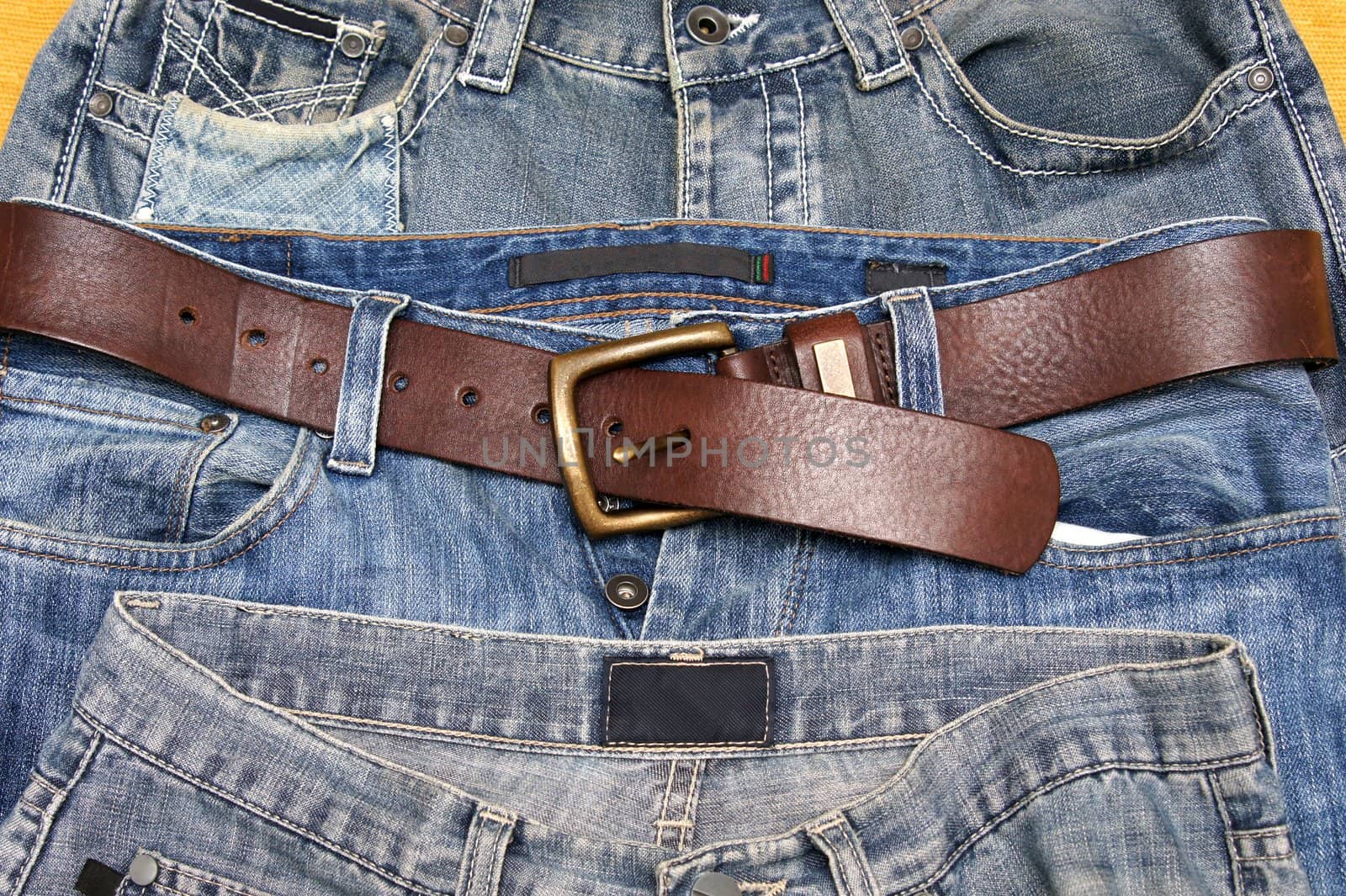 Three pairs of jeans pants and a belt