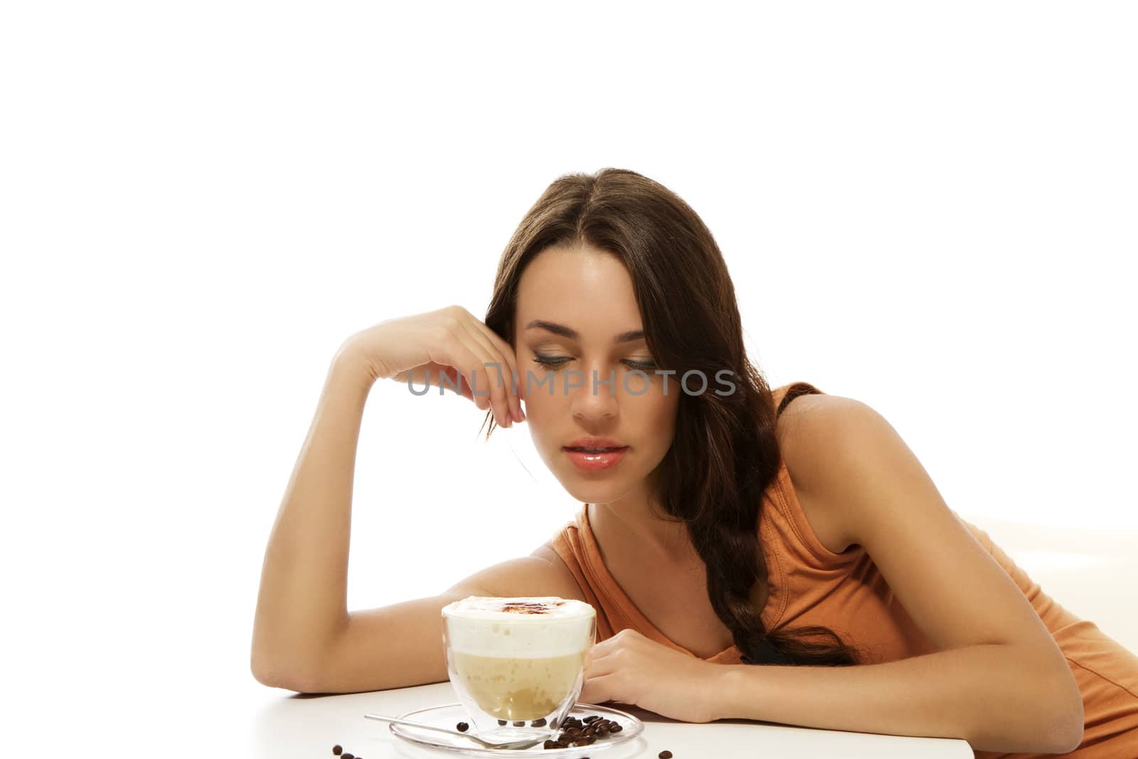 beautiful woman looking at the cappuccino coffee in front of her on the table on white background