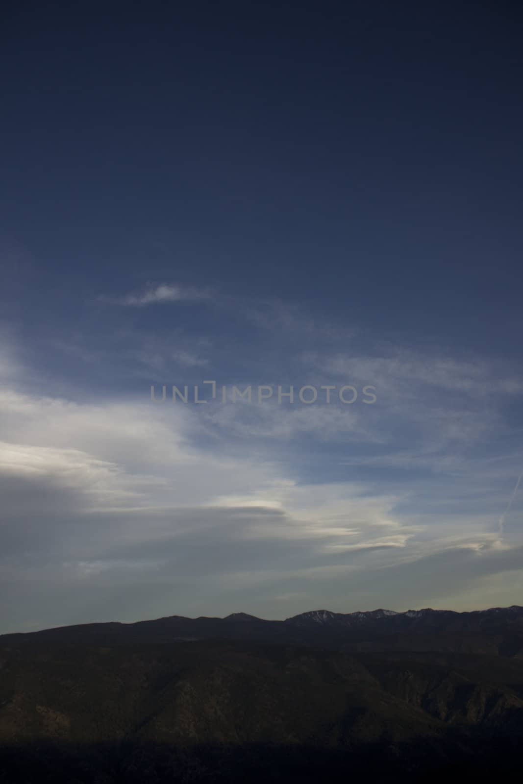 Clouds at dusk in the mountains. dark mountains and a bright blue sky.