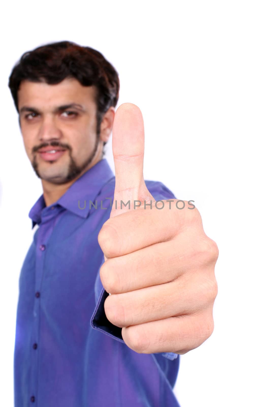 An Indian guy wishing good luck with a thumbs up sign, on white studio background. Focus on hand.