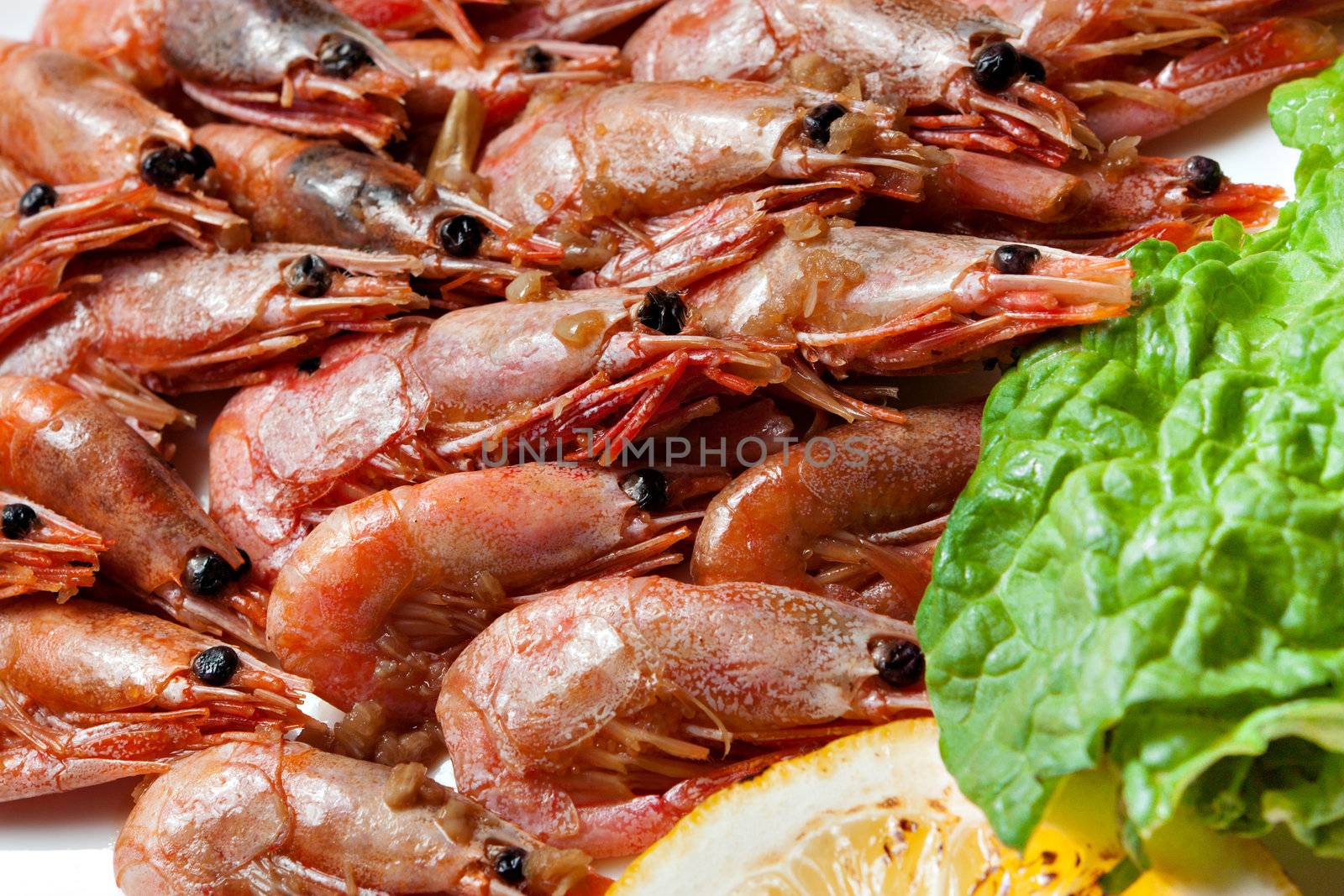 A lot of shrimp on the table with a green leaf.