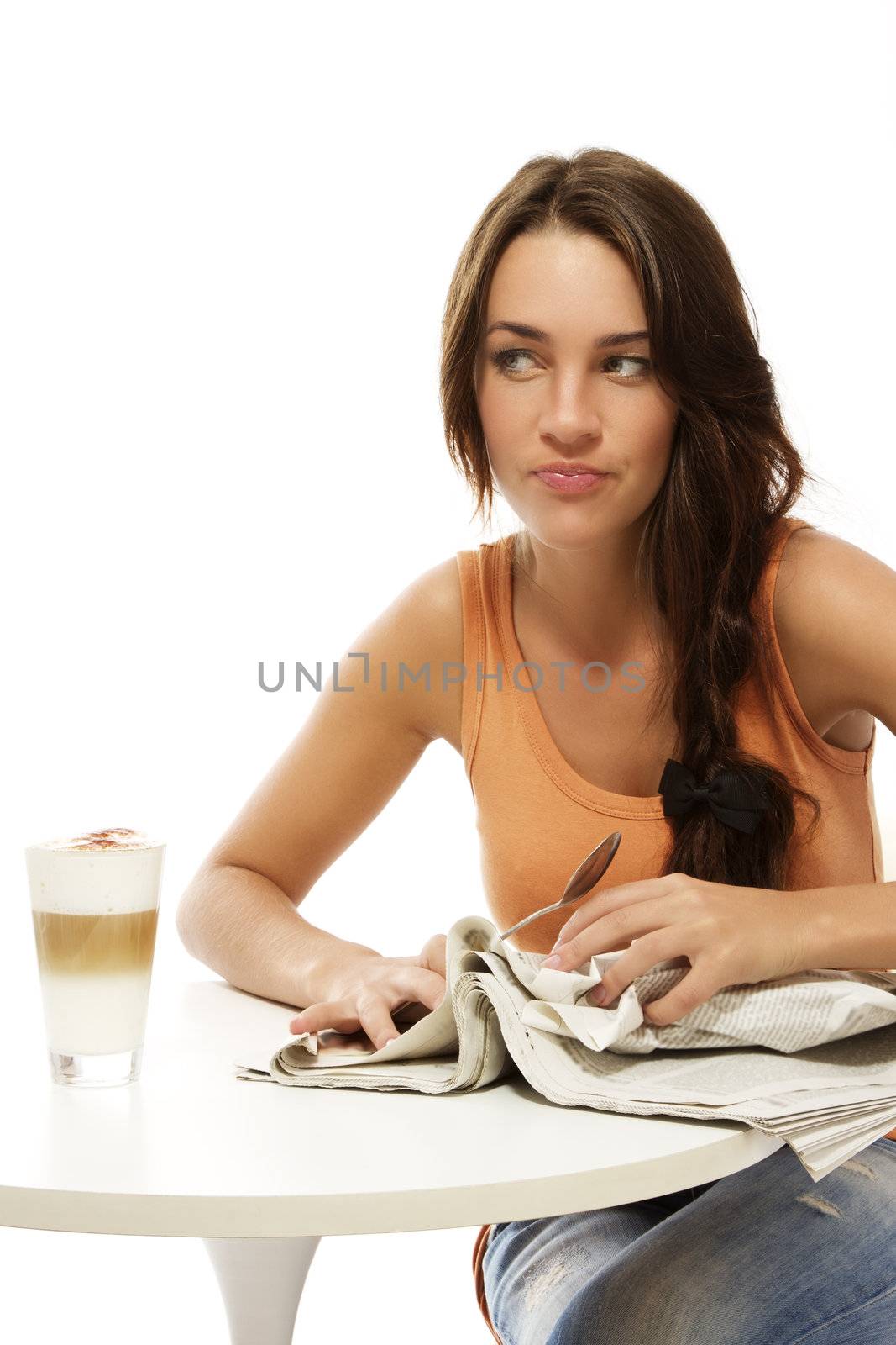 upset young woman with newspaper and latte macchiato at a table on white background