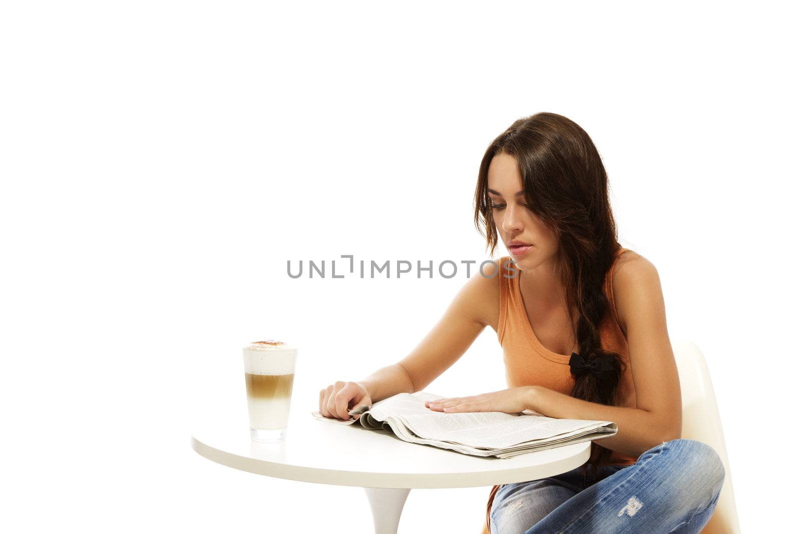 young woman reading newspaper at a table with latte macchiato coffee on white background
