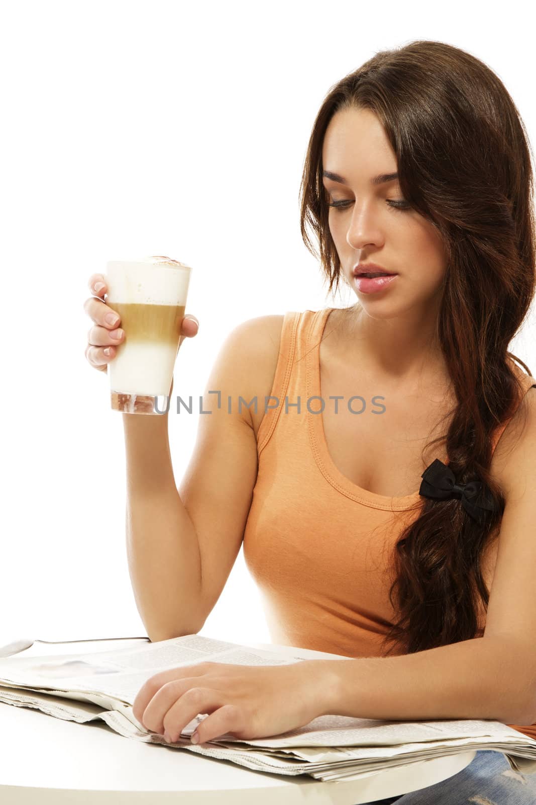 young woman sitting at a table reading newspaper holding latte macchiato coffee on white background