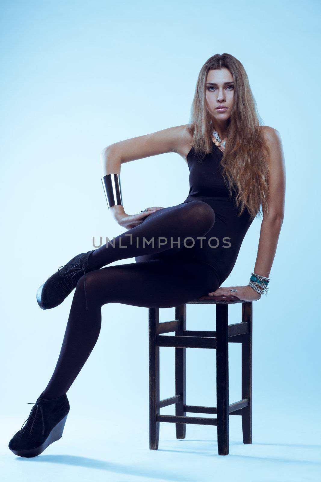 Young blonde woman in black swimsuit sitting on chair posing by vitmihailov