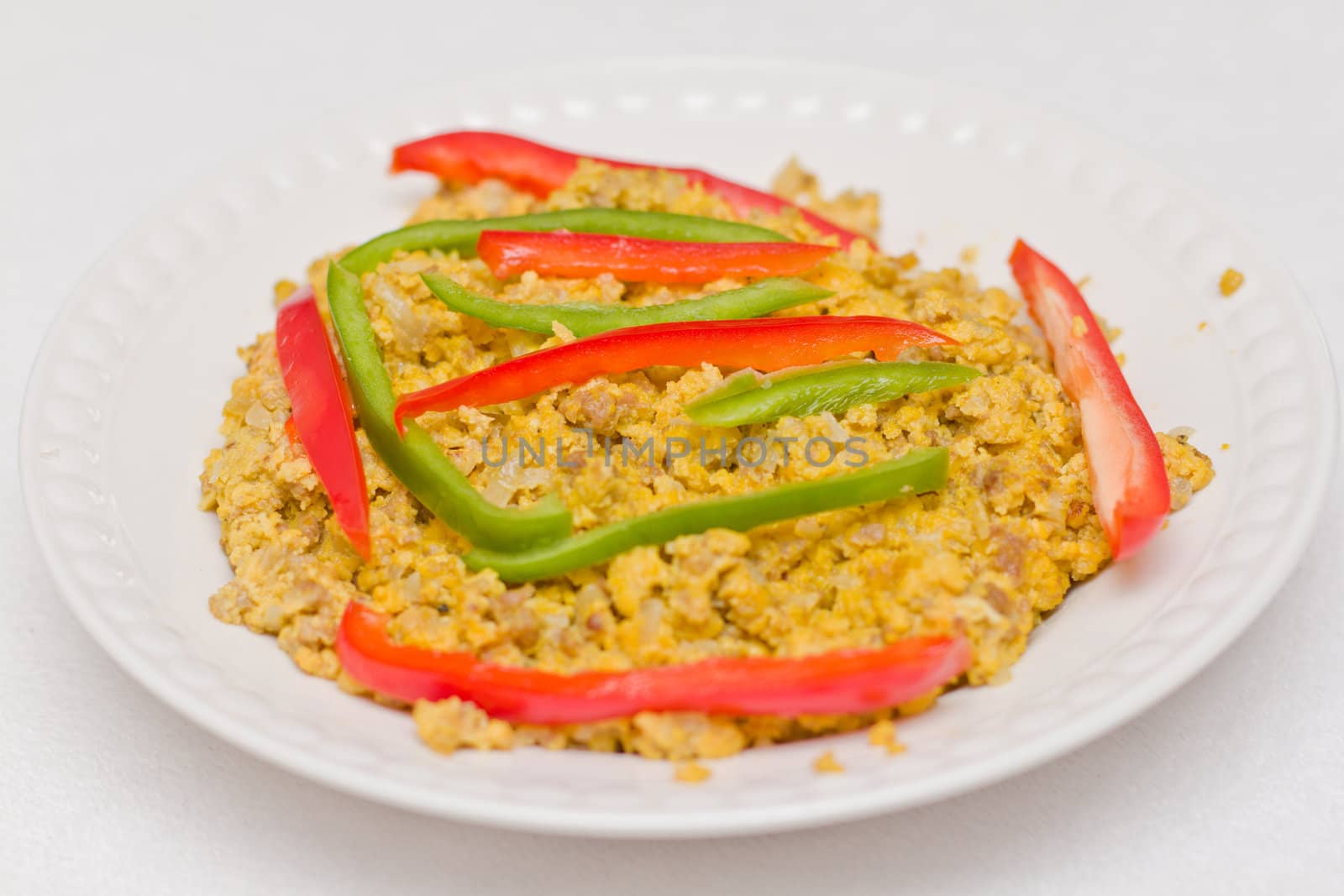 Scrambled eggs served on a plate with sliced bell peppers