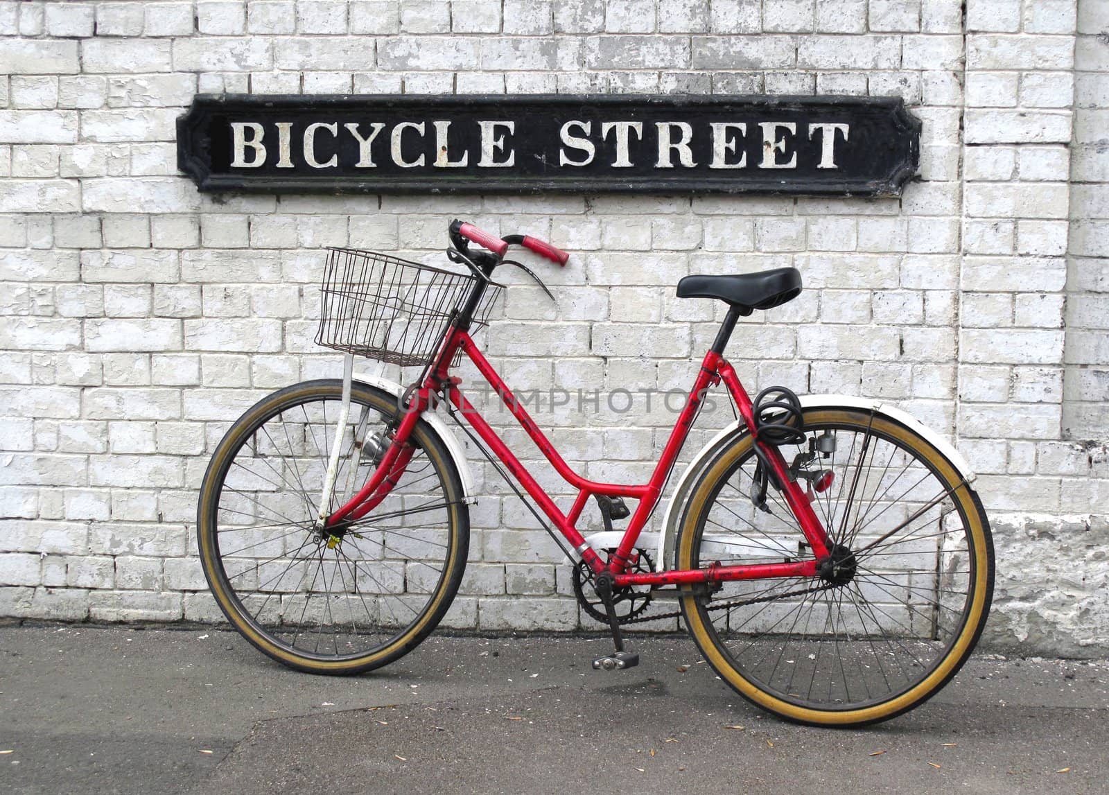 Bicycle against a white wall and a street sign Bicycle Street