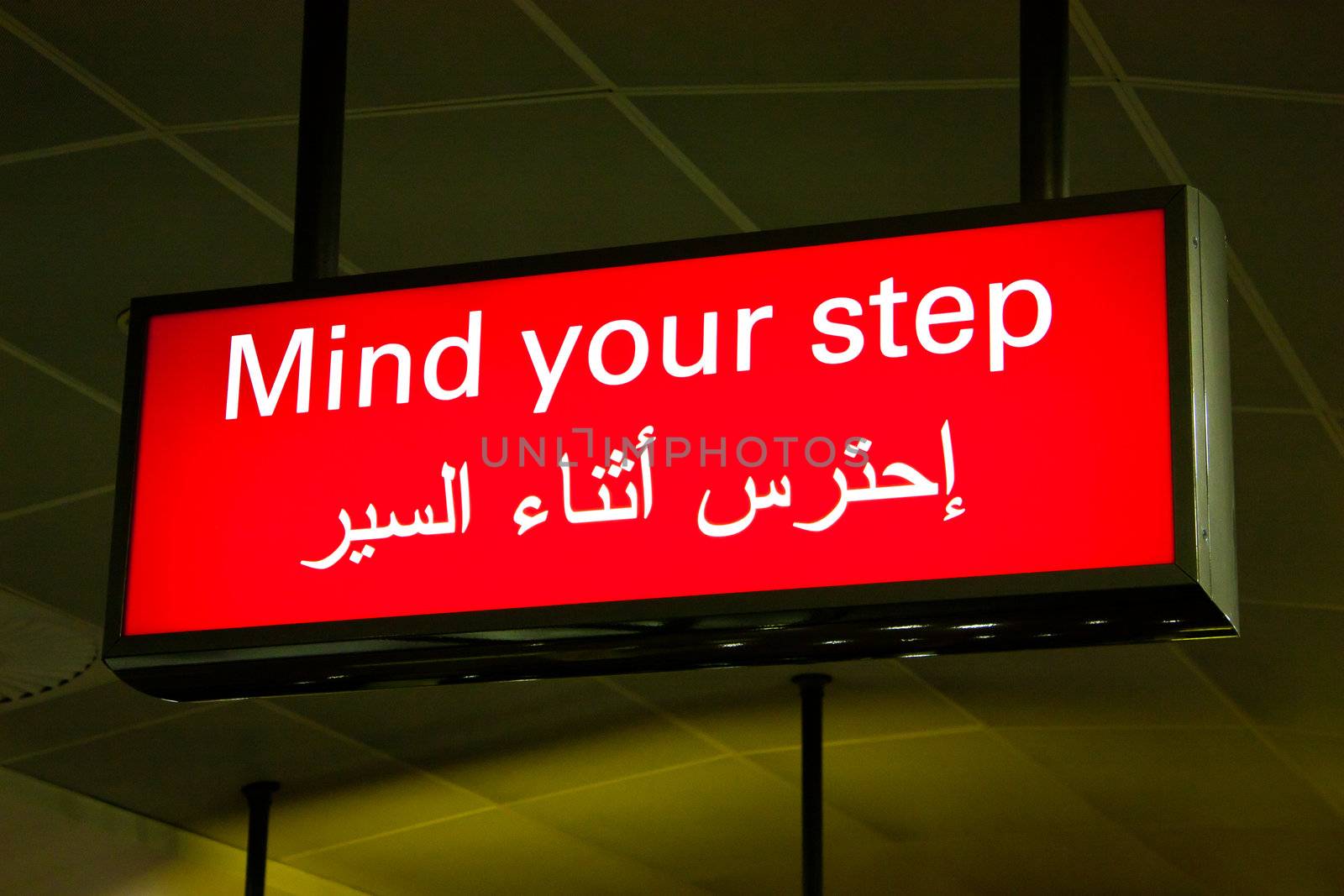 Mind your step sign in an international airport in Middle East with Arabic information