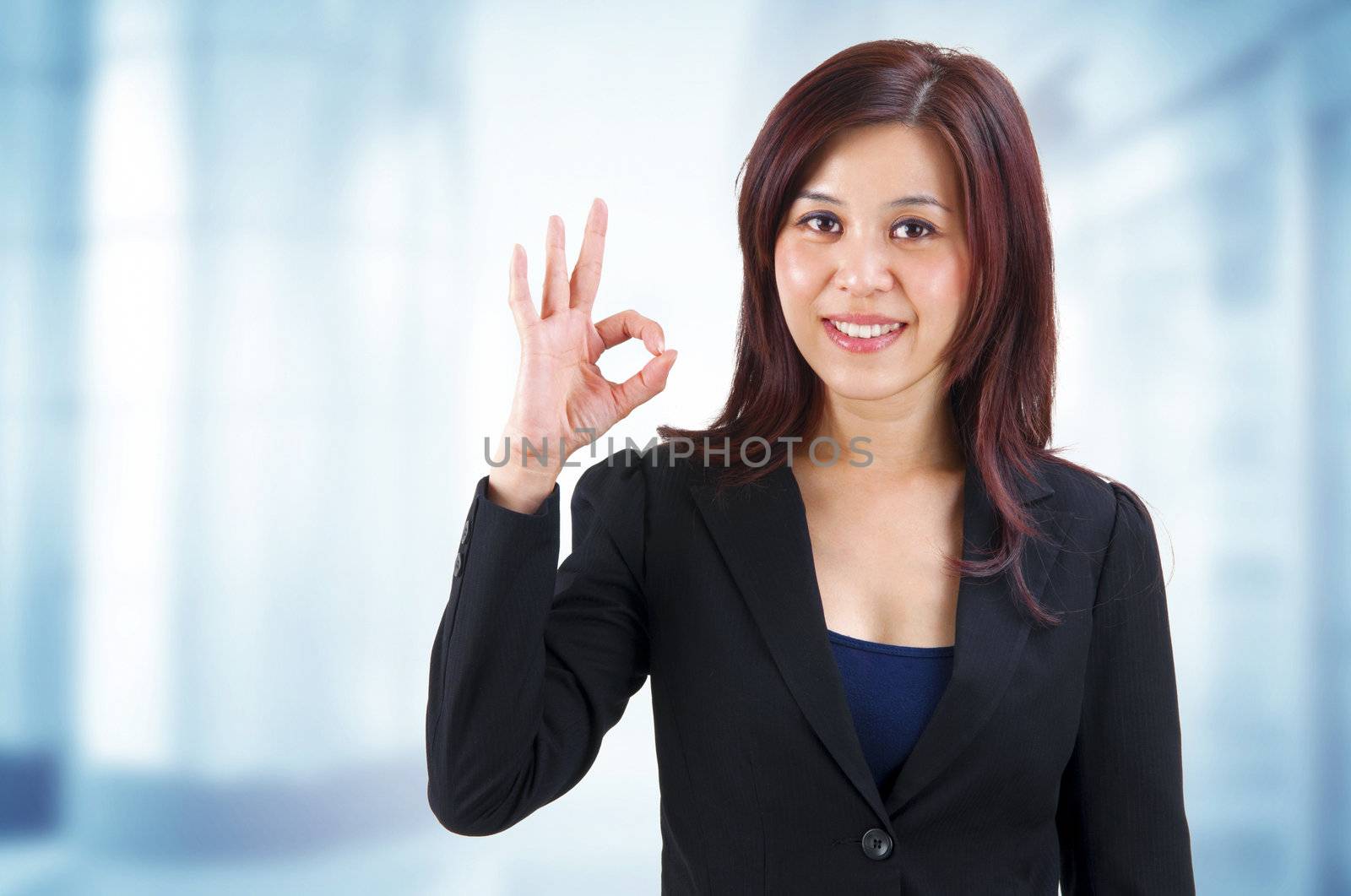 Mixed race Mid Adult Asian showing ok hand sign in work place