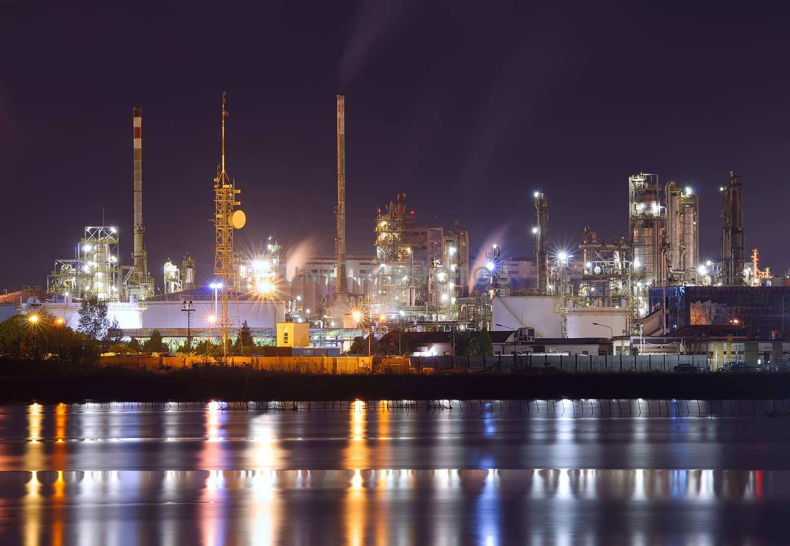 night scene of petrochemical plant with water reflection
