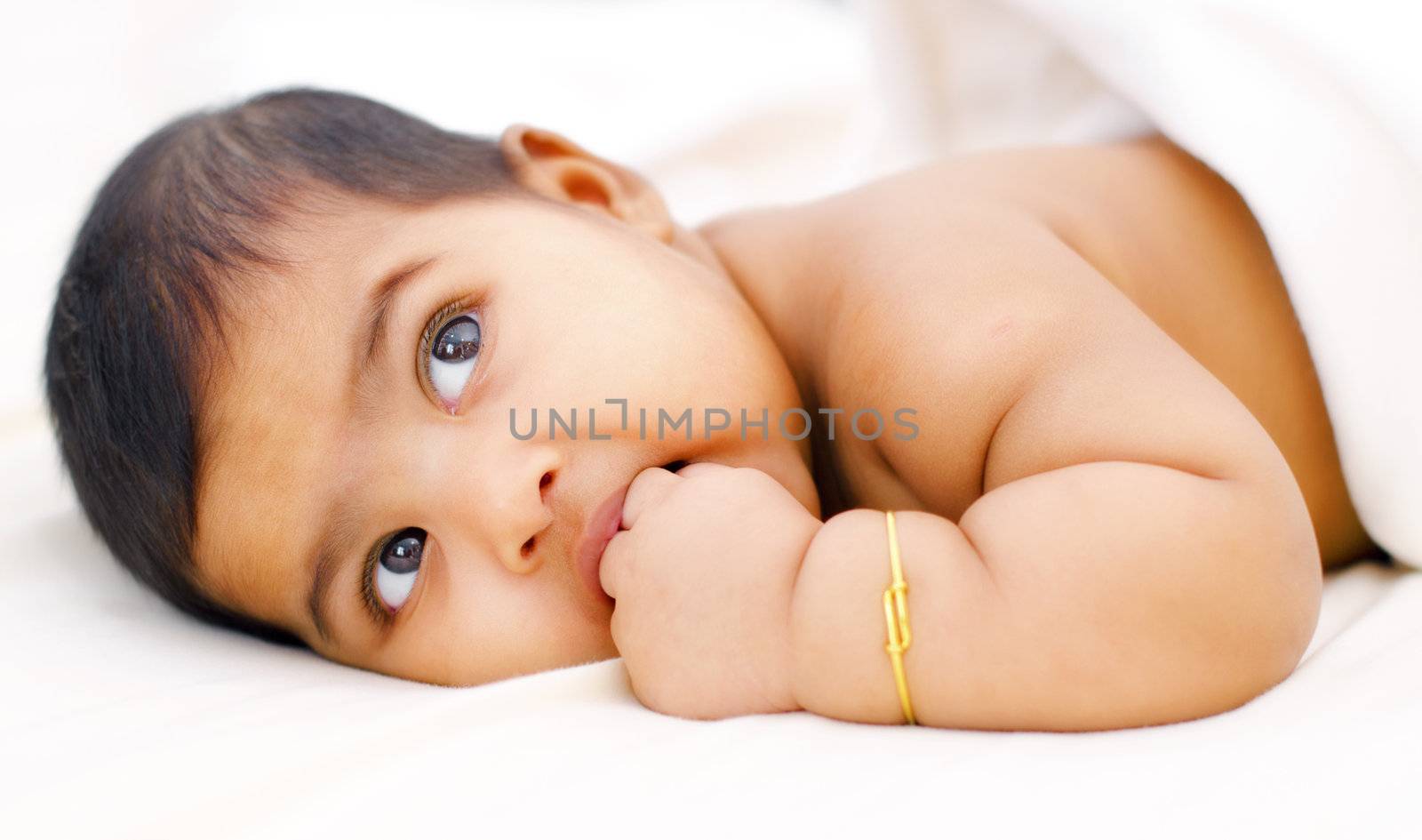 Six months old Indian baby girl sucking her fingers