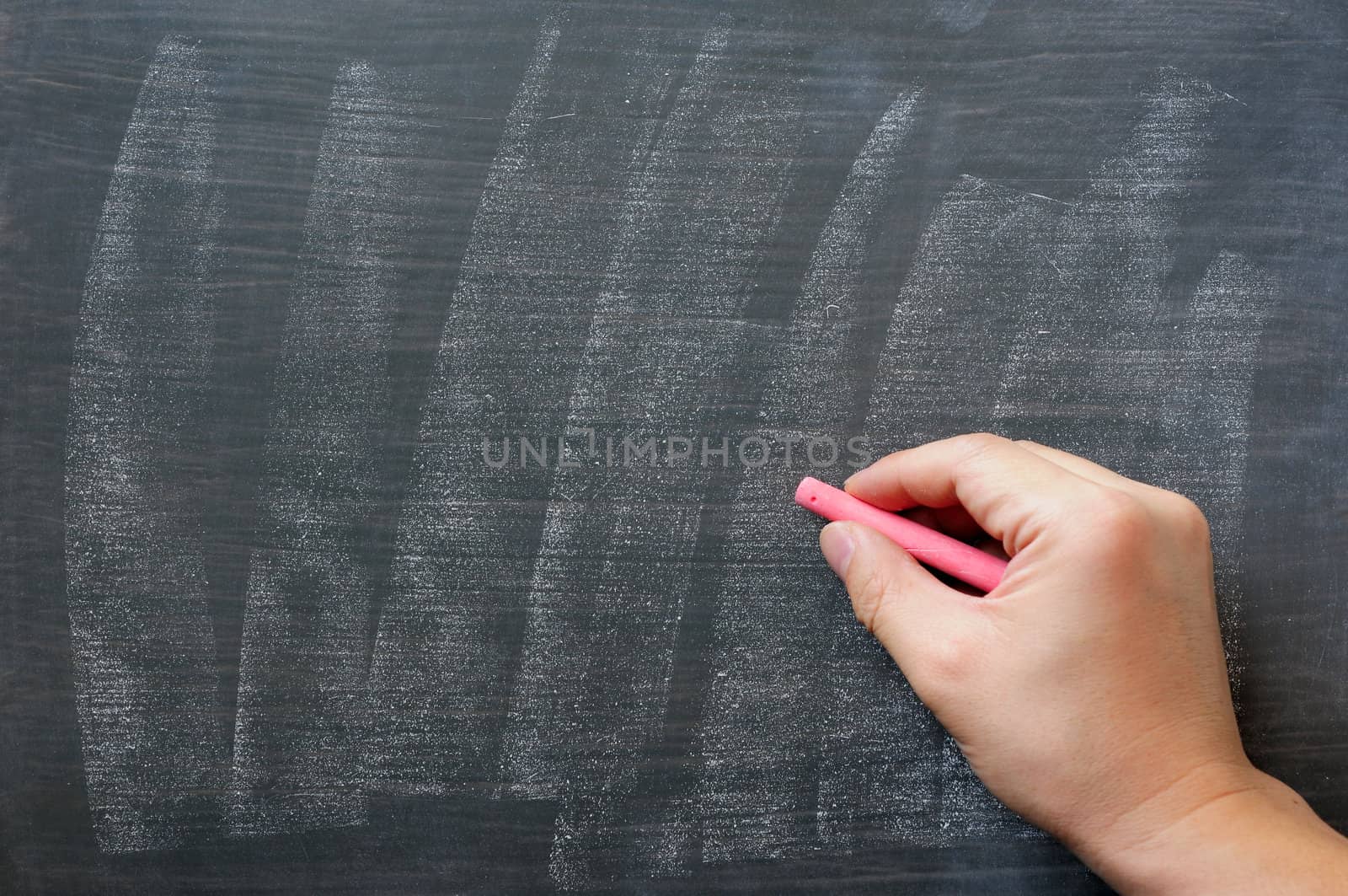 Blank blackboard / chalkboard. Hand writing on green chalk board holding red chalk. Great texture for text. 