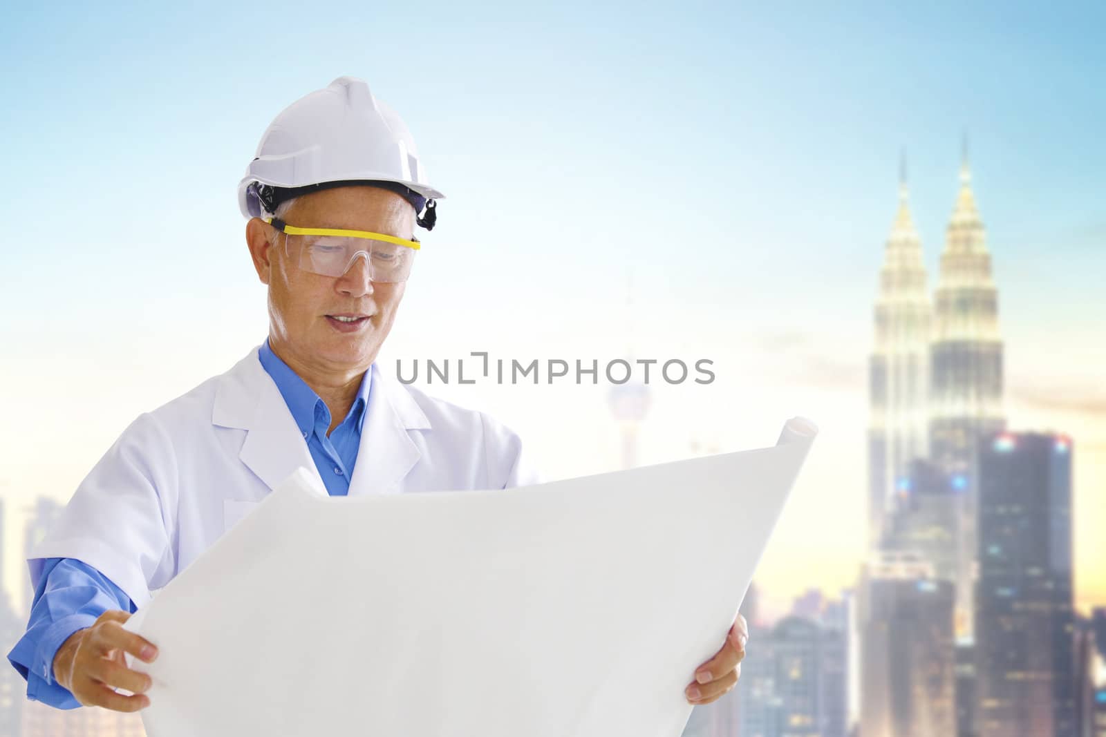Senior Asian engineer with blueprints standing outside modern building