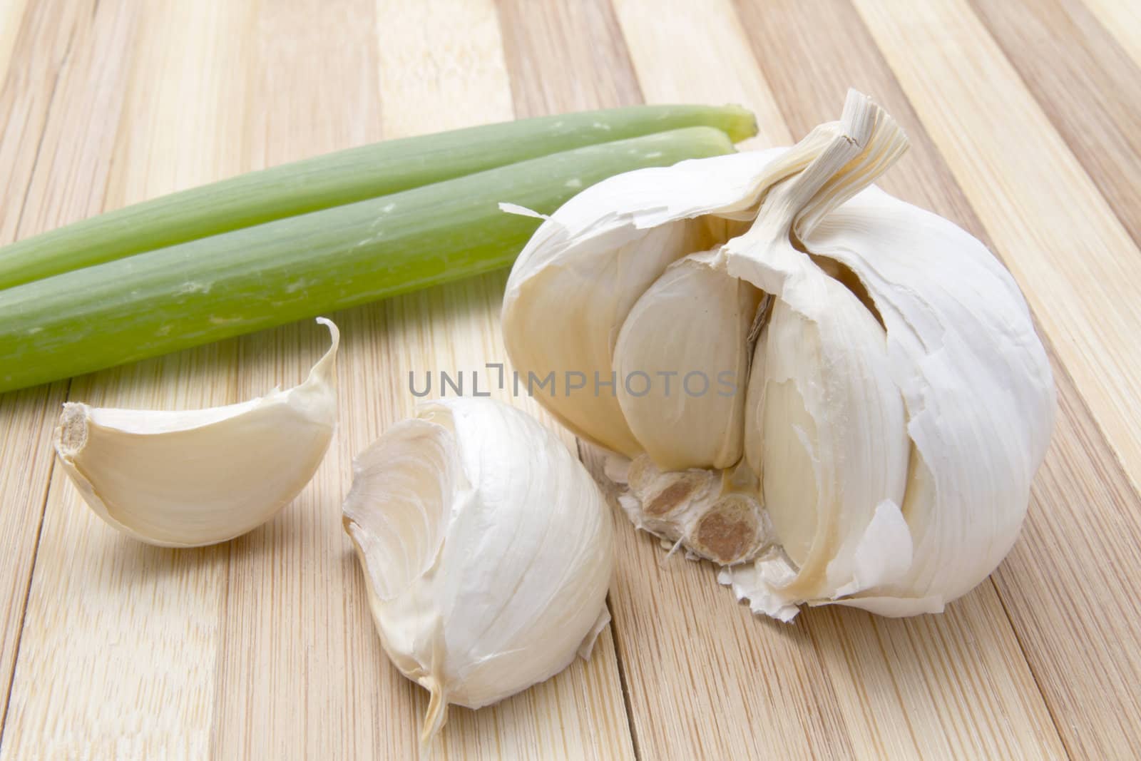 Fresh garlic and green onion closeup on wood bavkground