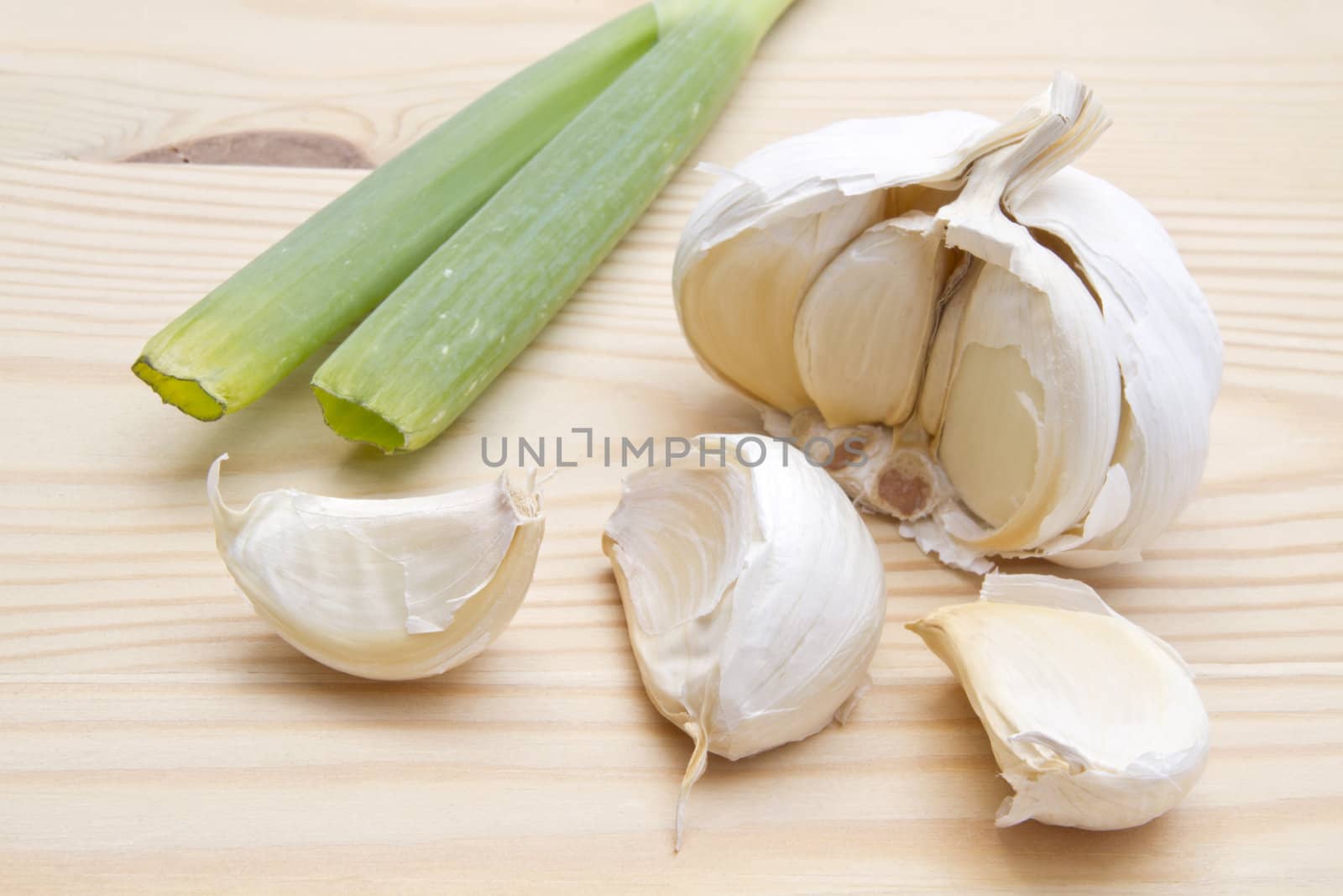 Fresh garlic and green onion closeup on wood background