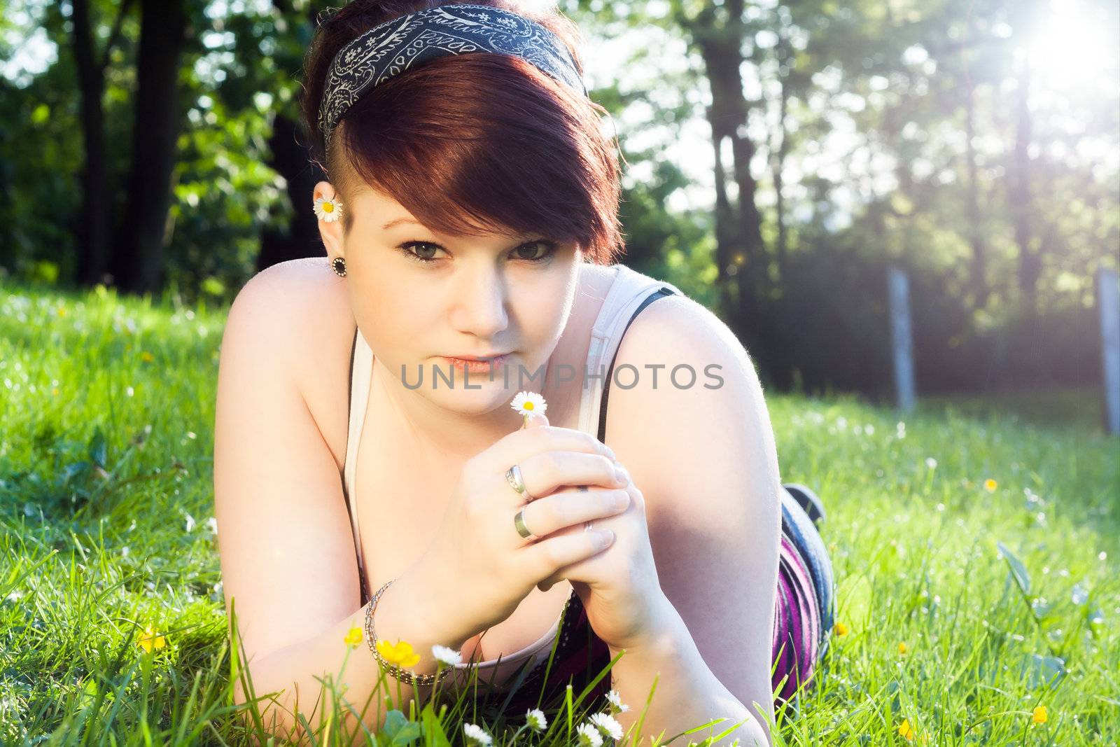 A beautiful young girl lying on the grass on a background of green