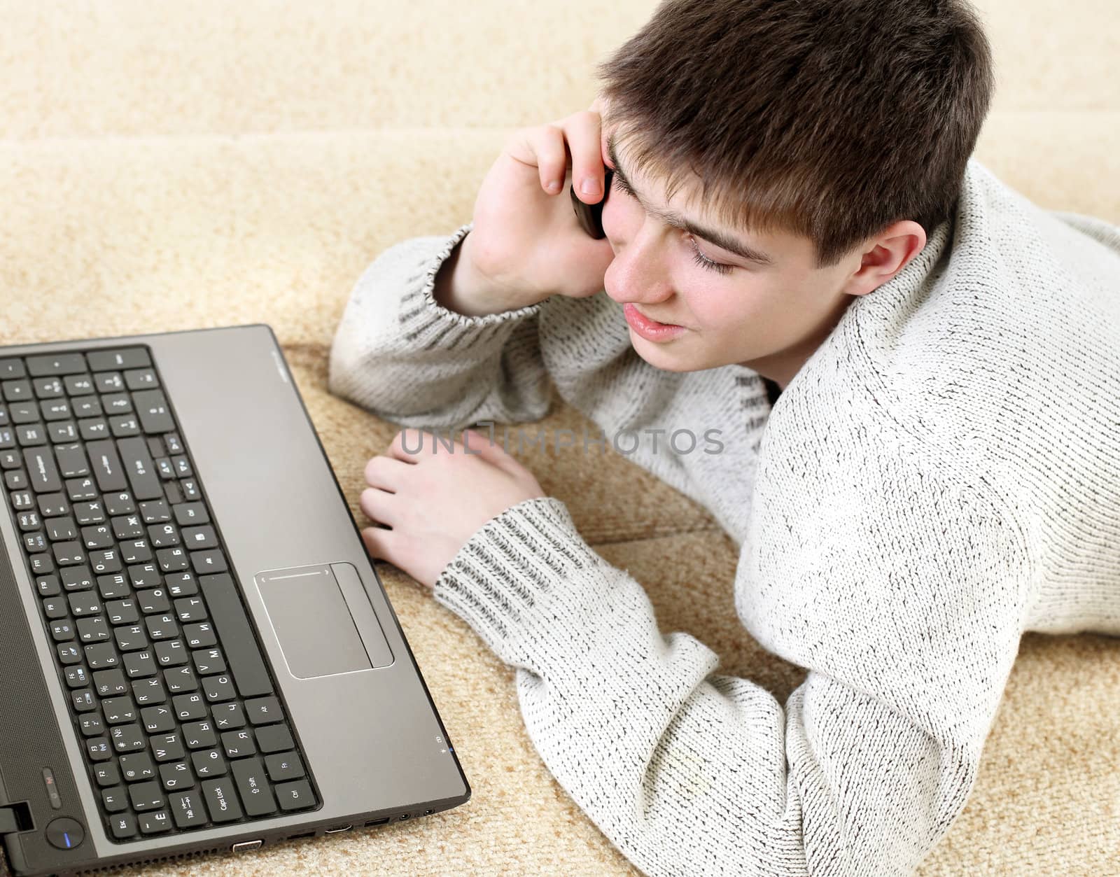 happy teenager with notebook talking on mobile phone in home interior