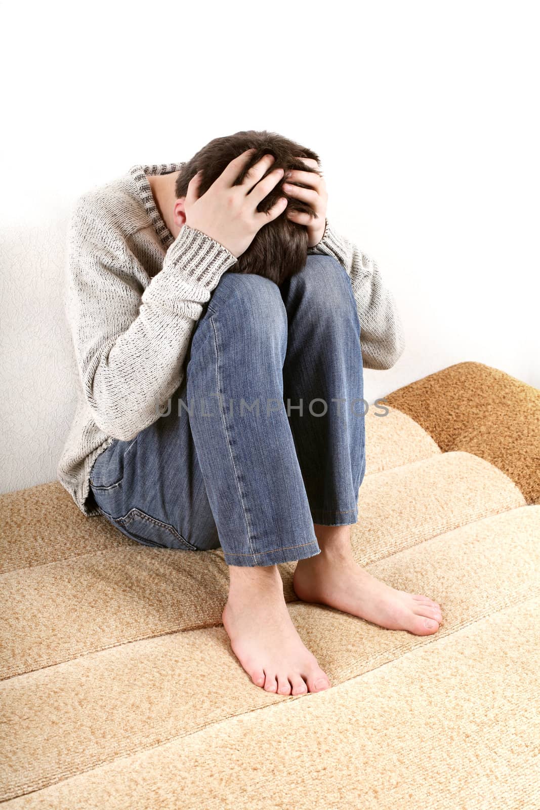 sad teenager sitting on the bed in home interior