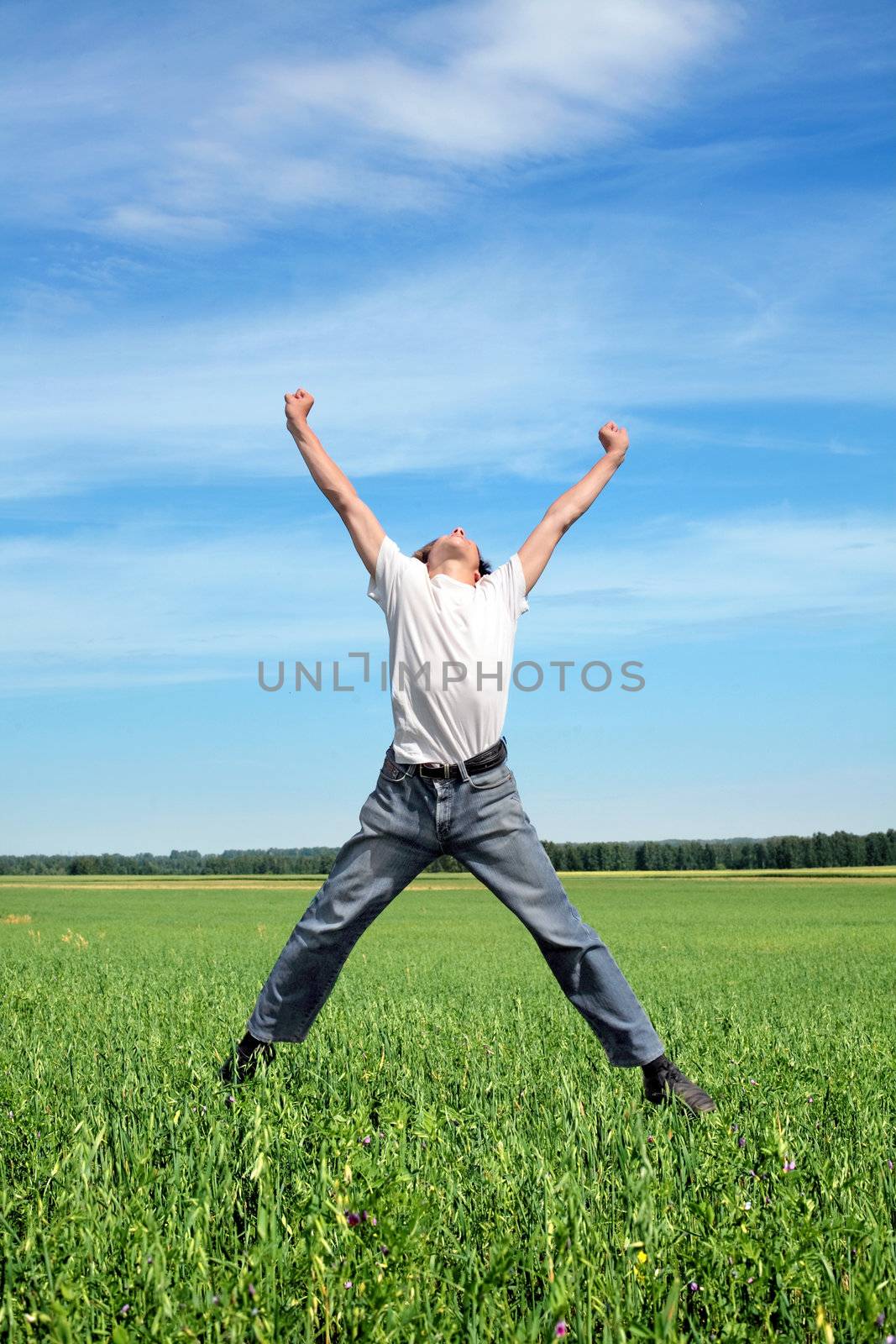 Happy young person jumping on the summer meadow