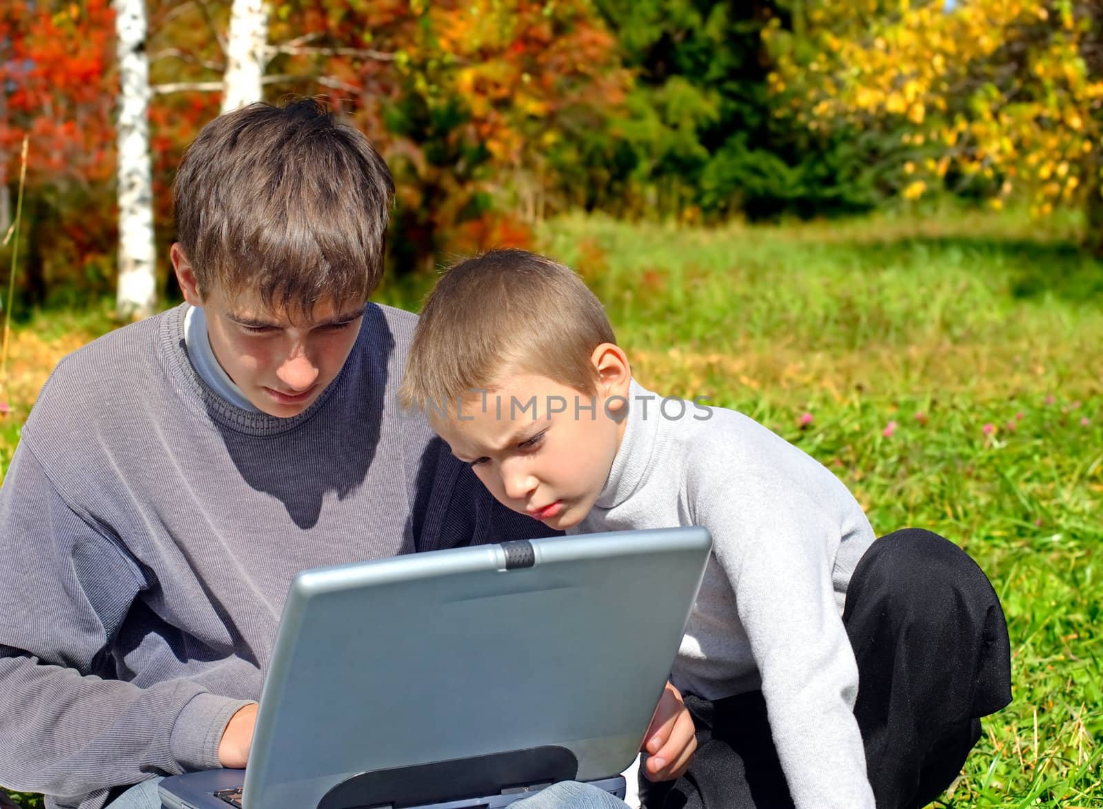 serious teenager and kid with notebook outdoor