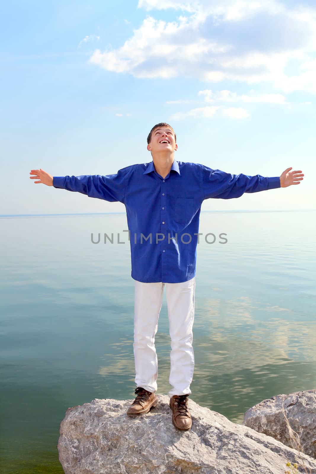 happy young man with hands up on the seaside background