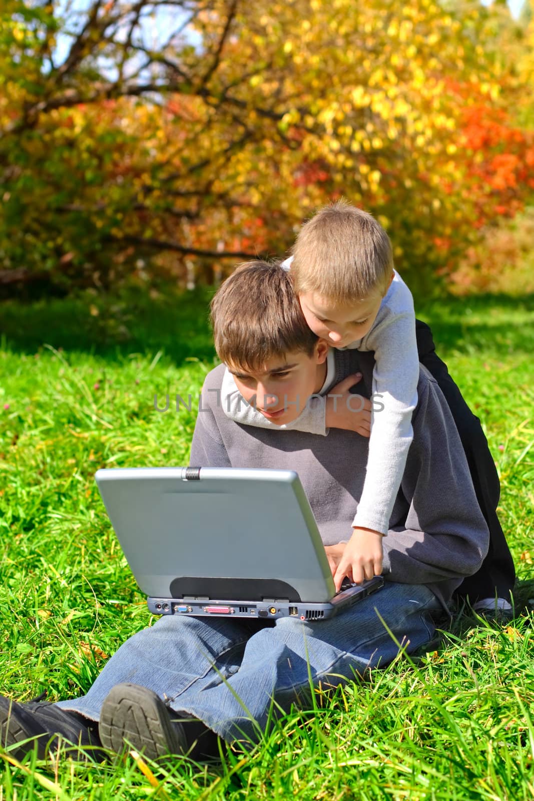 teenager and kid with laptop on the meadow