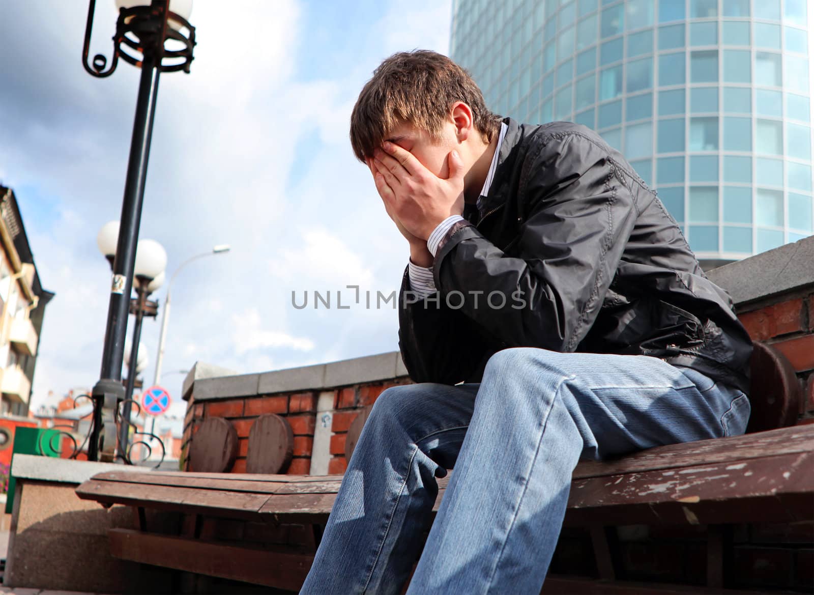 sorrowful young man sitting on the city street