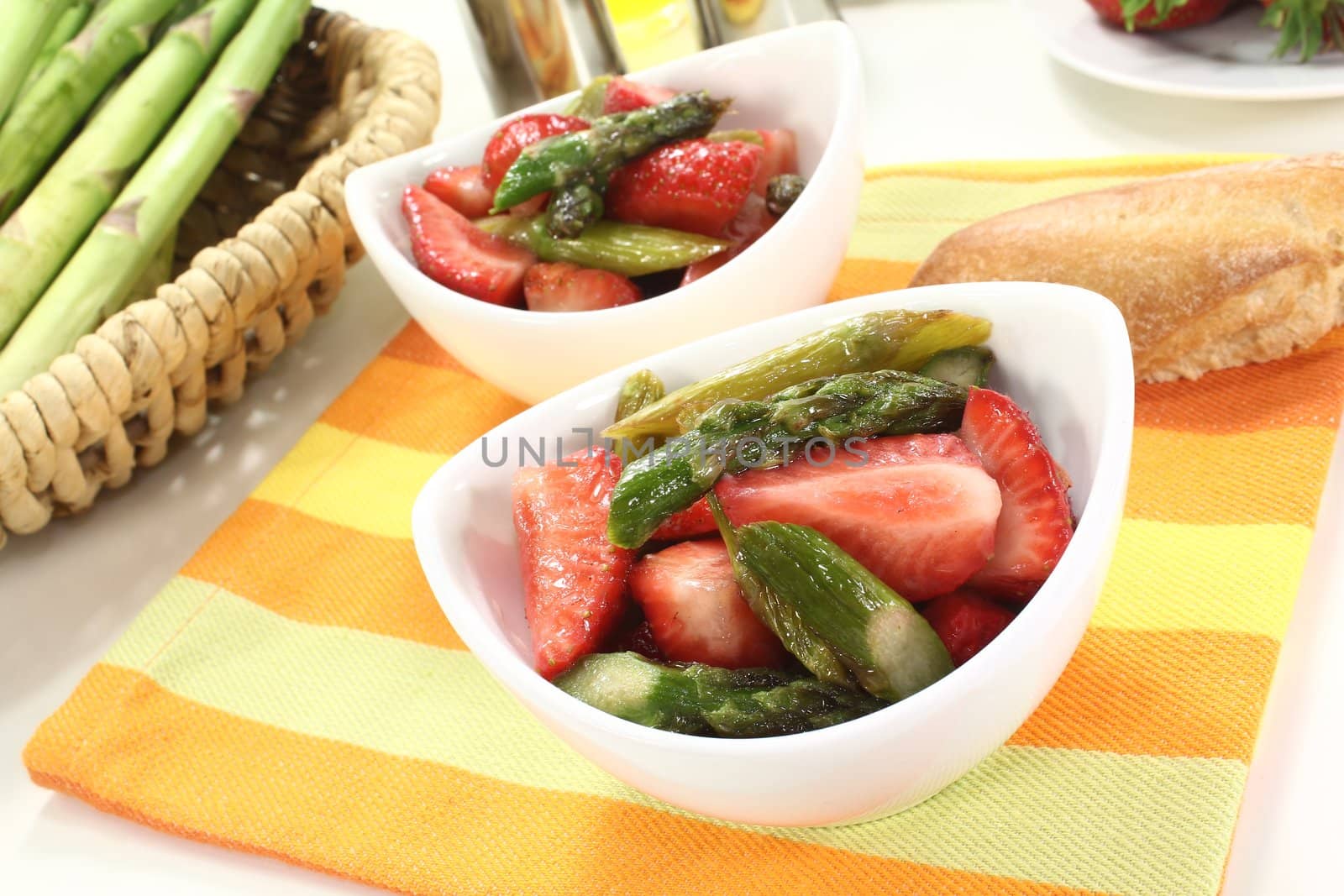 fresh Asparagus salad with strawberries and bread on a bright background