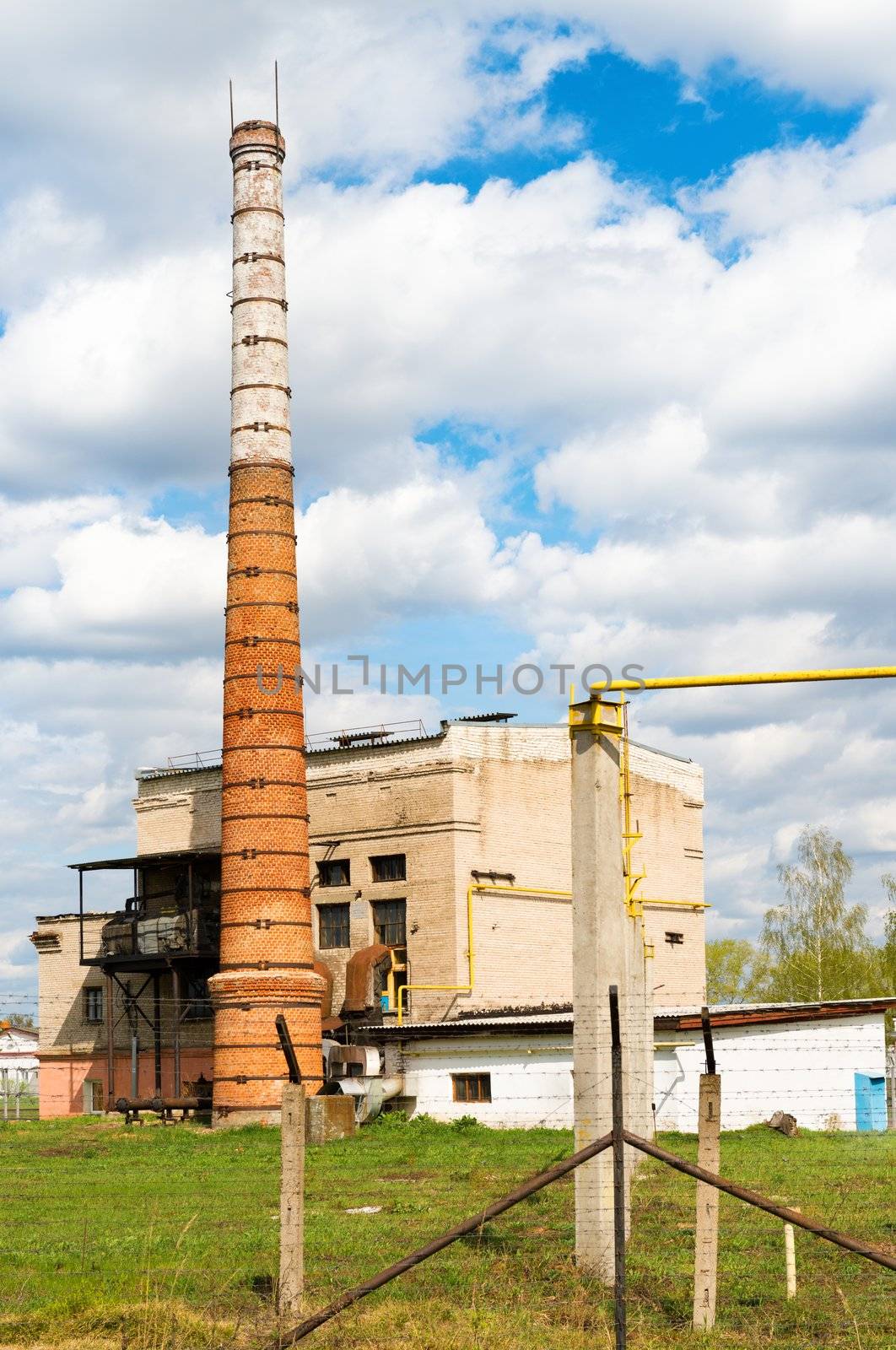 Boiler house with high stack and metal fence in front