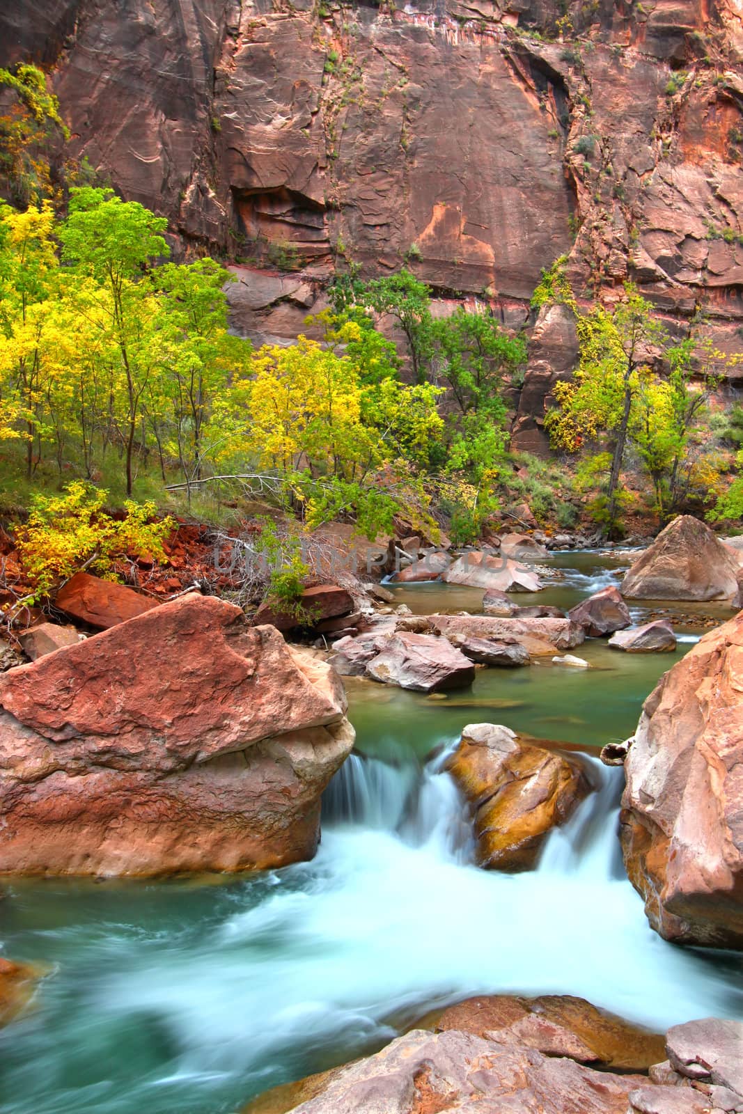 Small Virgin River waterfall through large boulders in Zion Canyon of Utah.