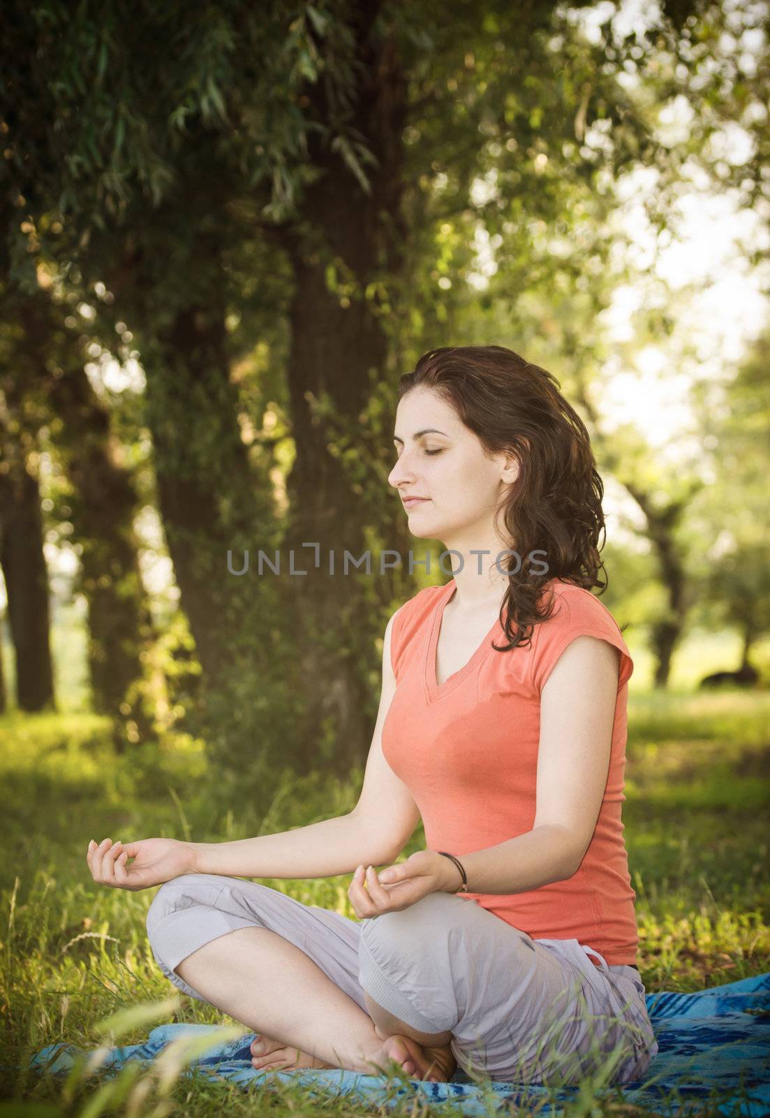 Young women in lotus position trying a breathing exercise in nature