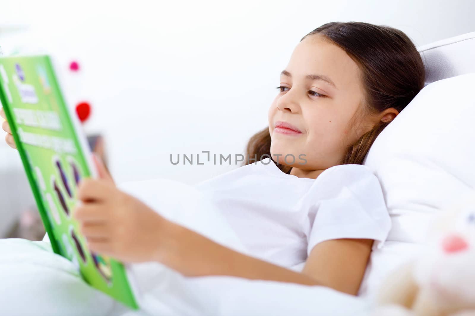 Portrait of girl with a book in bed at home