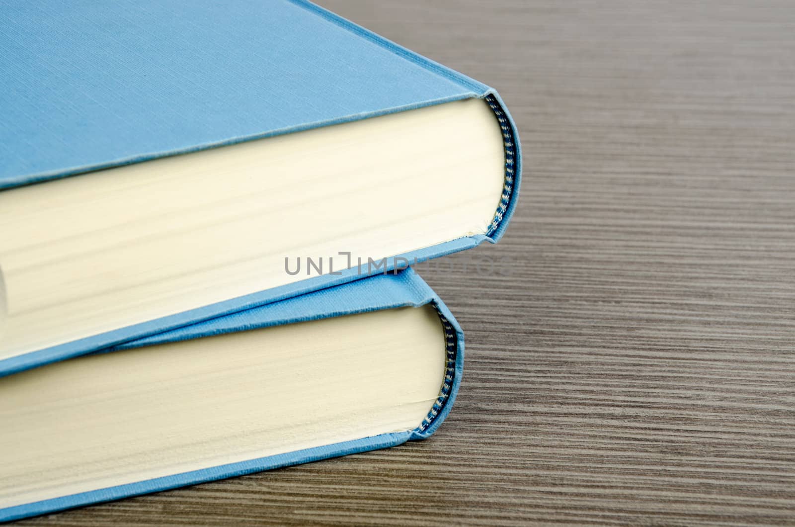 Two blue books on a table with wooden texture