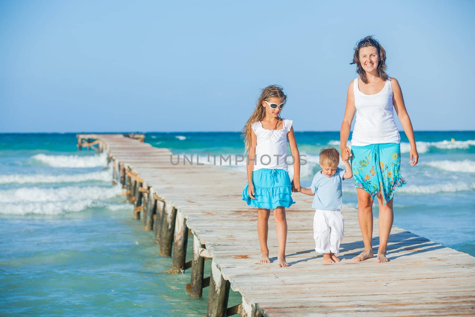 Family of three on jetty by the ocean by maxoliki