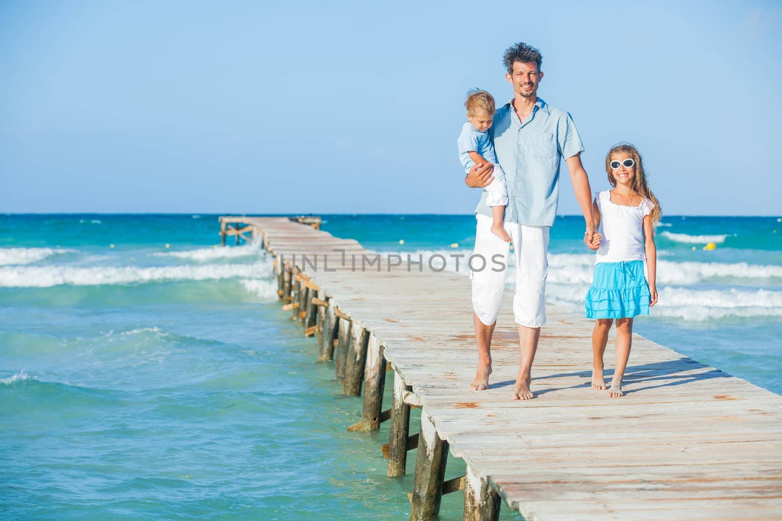 Family of three on jetty by the ocean by maxoliki