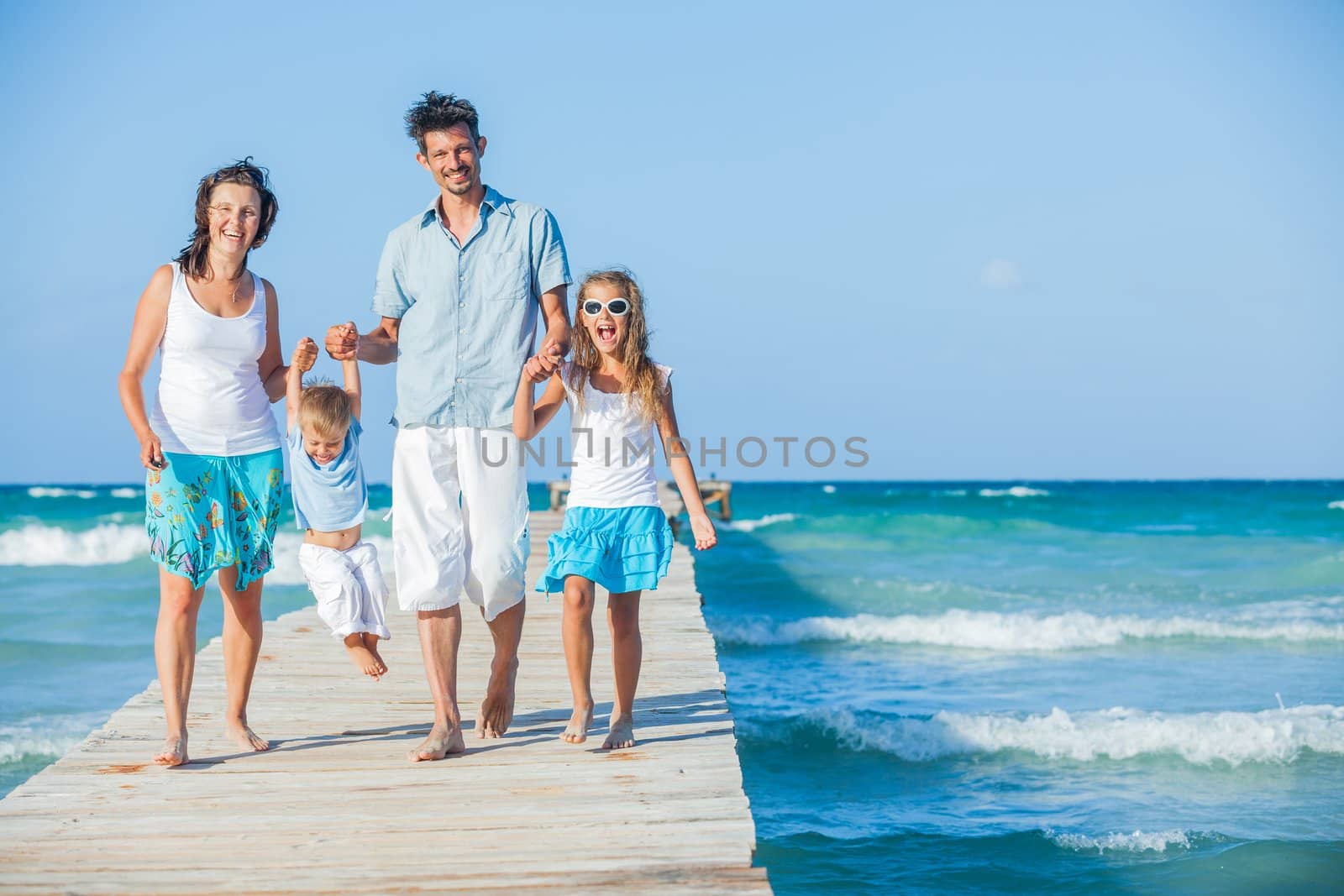 Family of four on jetty by the ocean by maxoliki