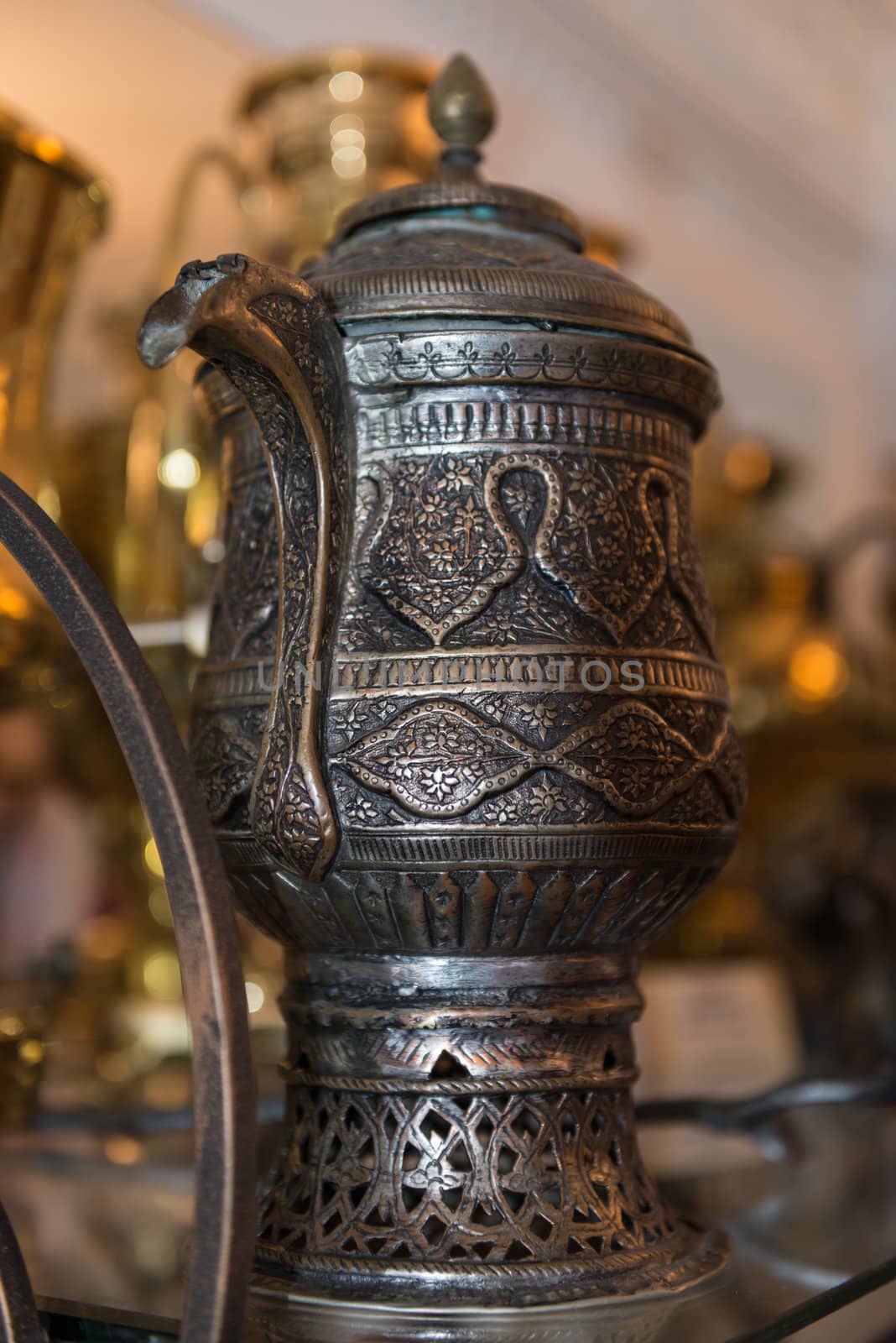 Vintage decorated black teapot on a shelf. Selective focus on front.