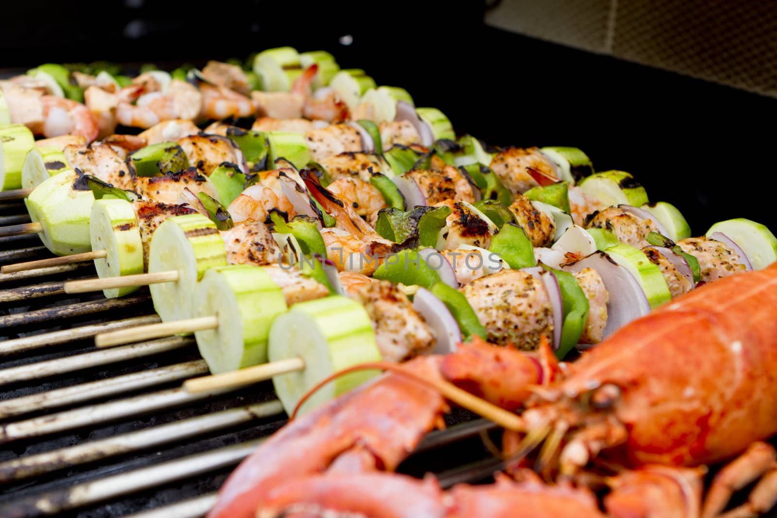 Salmon and Vegetable Skewers and Lobster are on the barbecue.