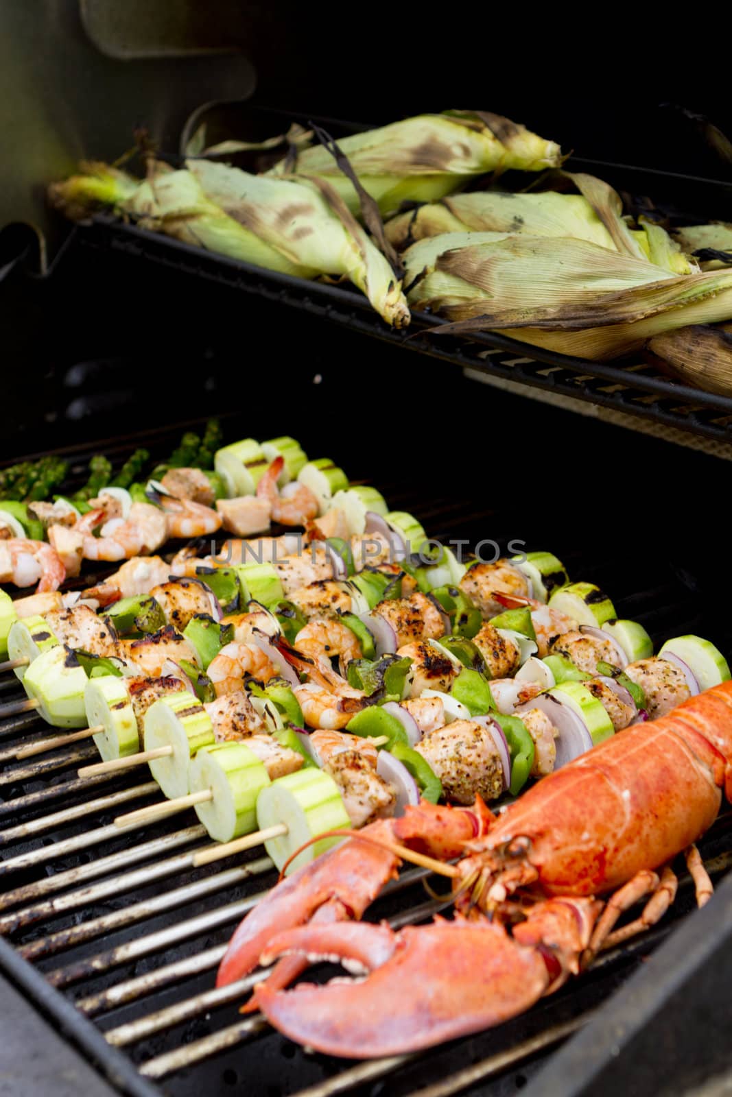 Salmon Skewers, Lobster and cornstalks are on the barbecue.
