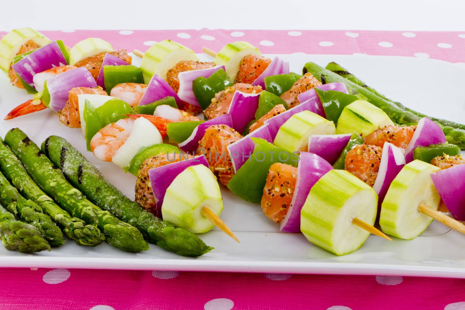 Salmon cubes and Shrimp complimented with vegetables on skewers. Ready to cook. Red onions, zucchini, green peppers and asparagus.