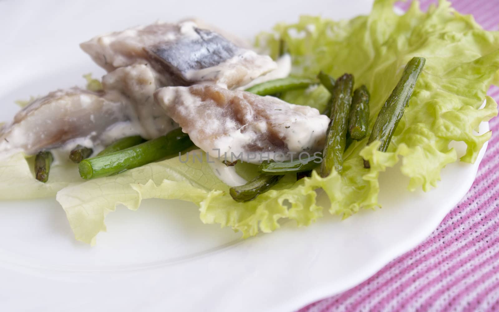 Appetizing marinaded herring with fried stalks of garlic